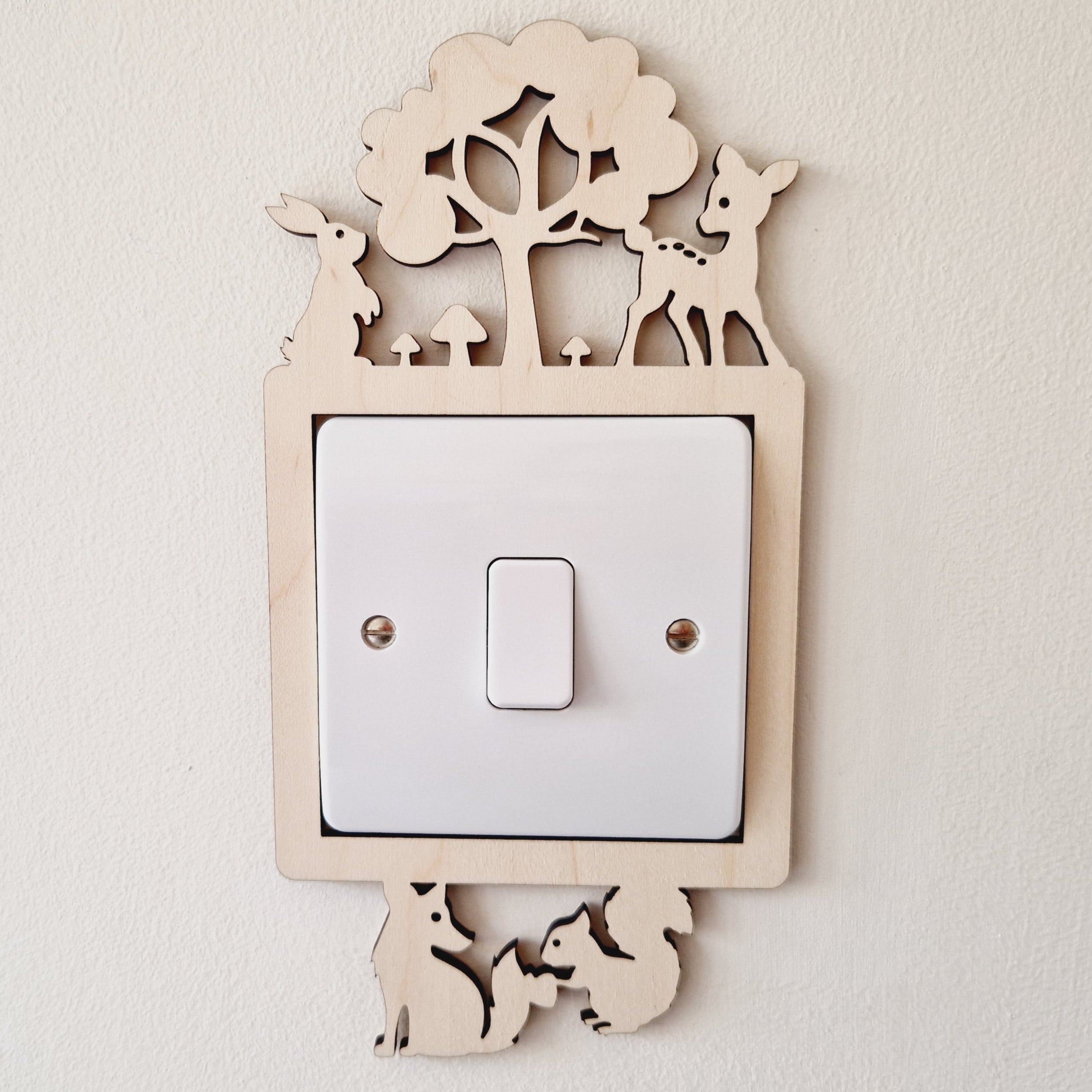 Decorative light switch cover with woodland bunny, deer, fox and squirrel animal design on a plain wall.
