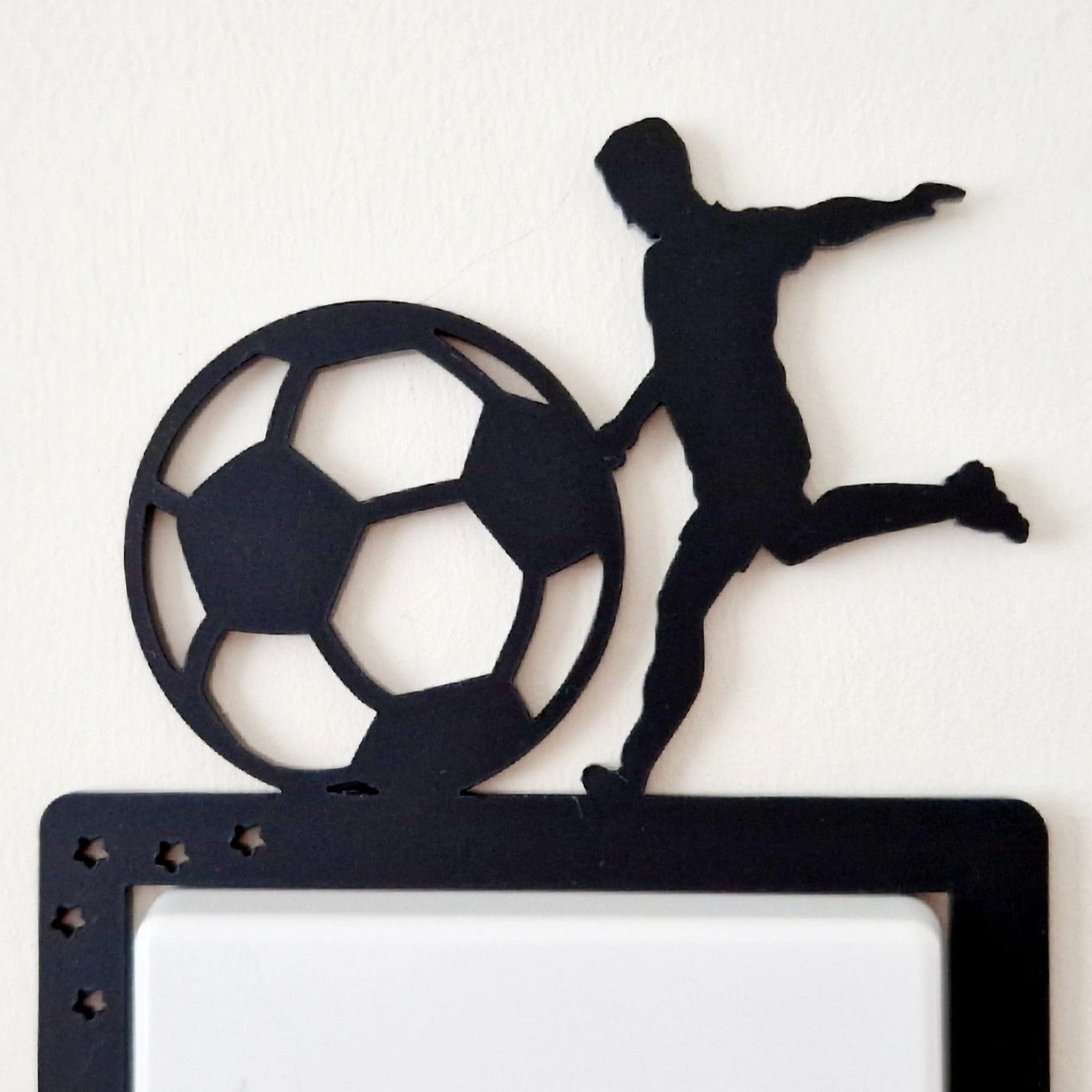 Decorative wall switch with a silhouette of a soccer player and ball on a white background
