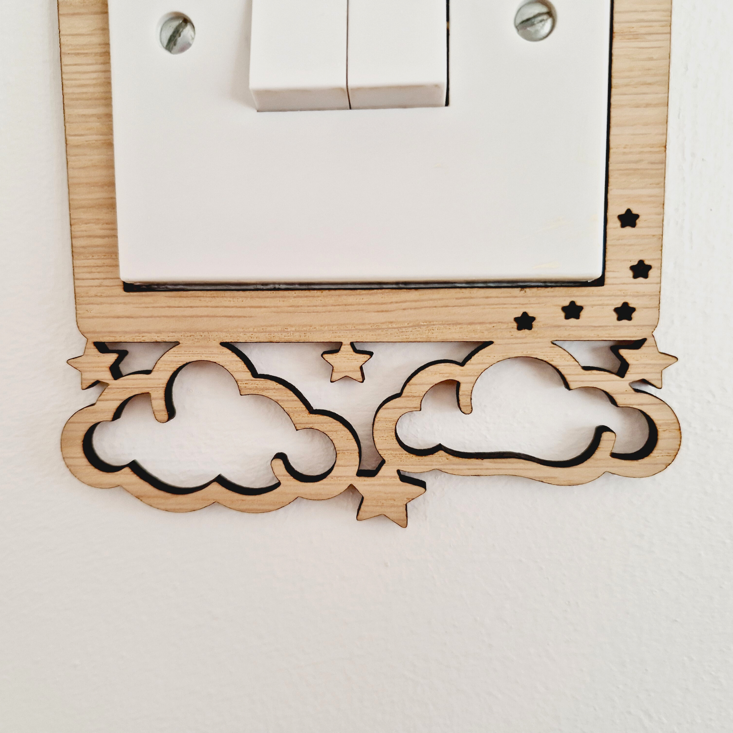 a wooden light switch with a decorative design featuring clouds and stars carved into the switch itself.