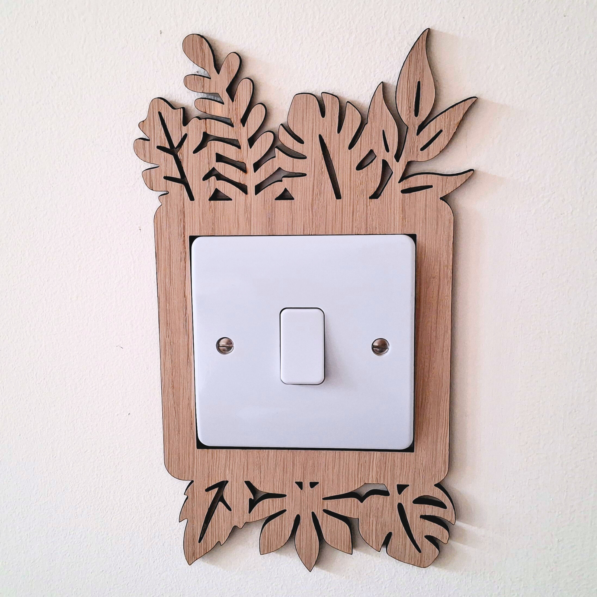 A wooden light switch with a leaf-shaped design on the top and bottom edges, mounted on a white wall.