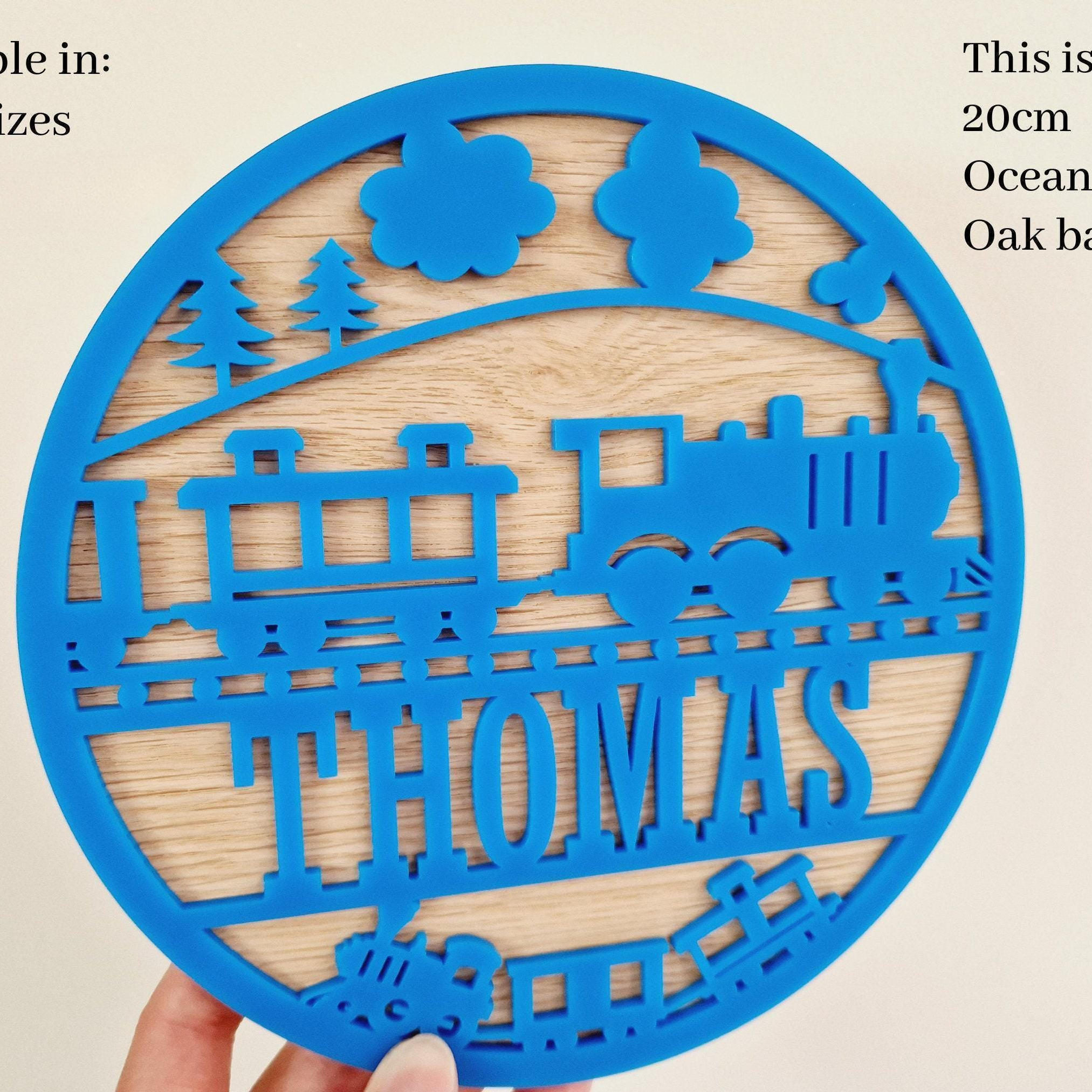 a blue circular cutout with a train design, and the name "THOMAS" written on it.