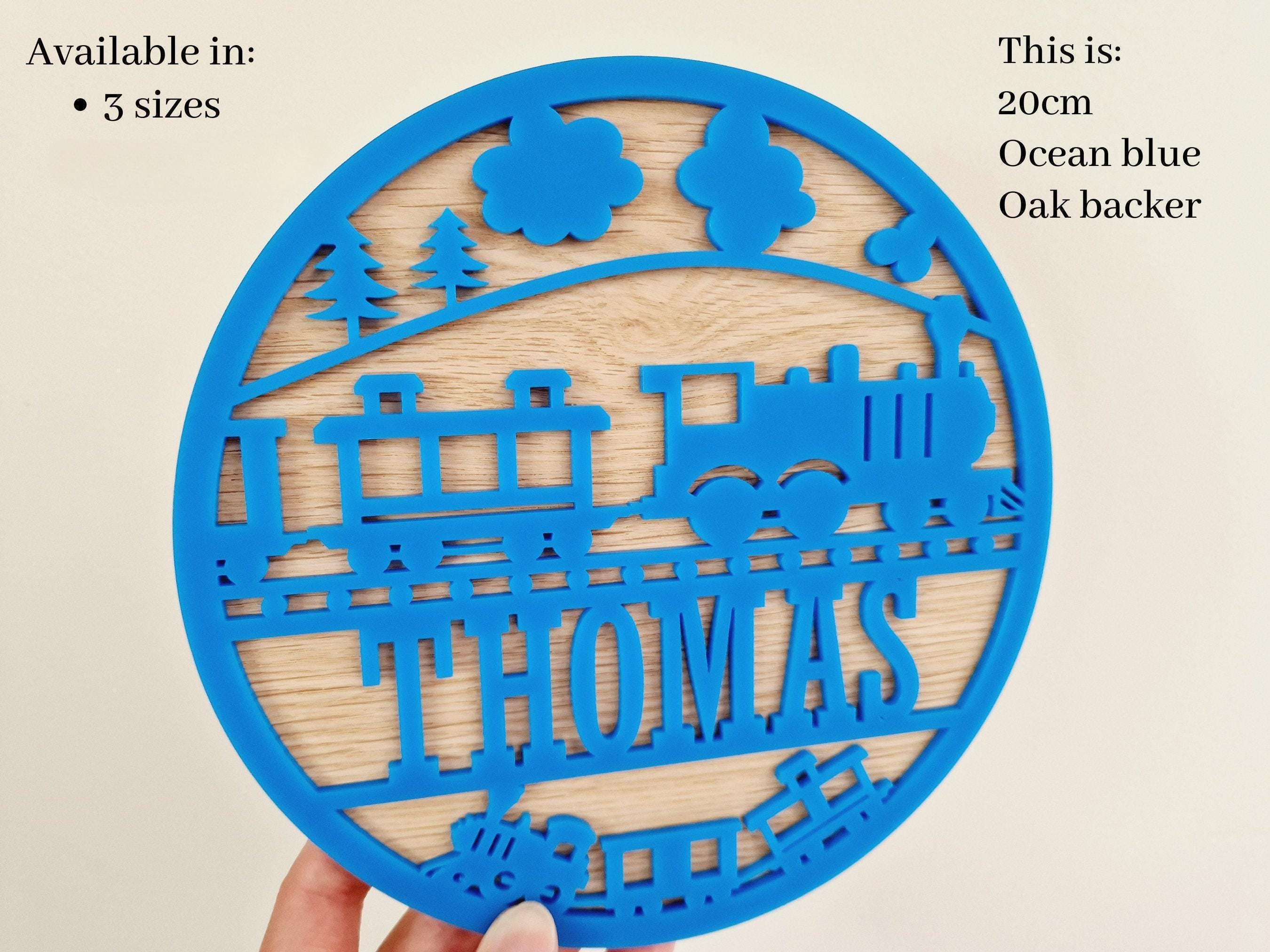 a blue circular cutout with a train design, and the name "THOMAS" written on it.
