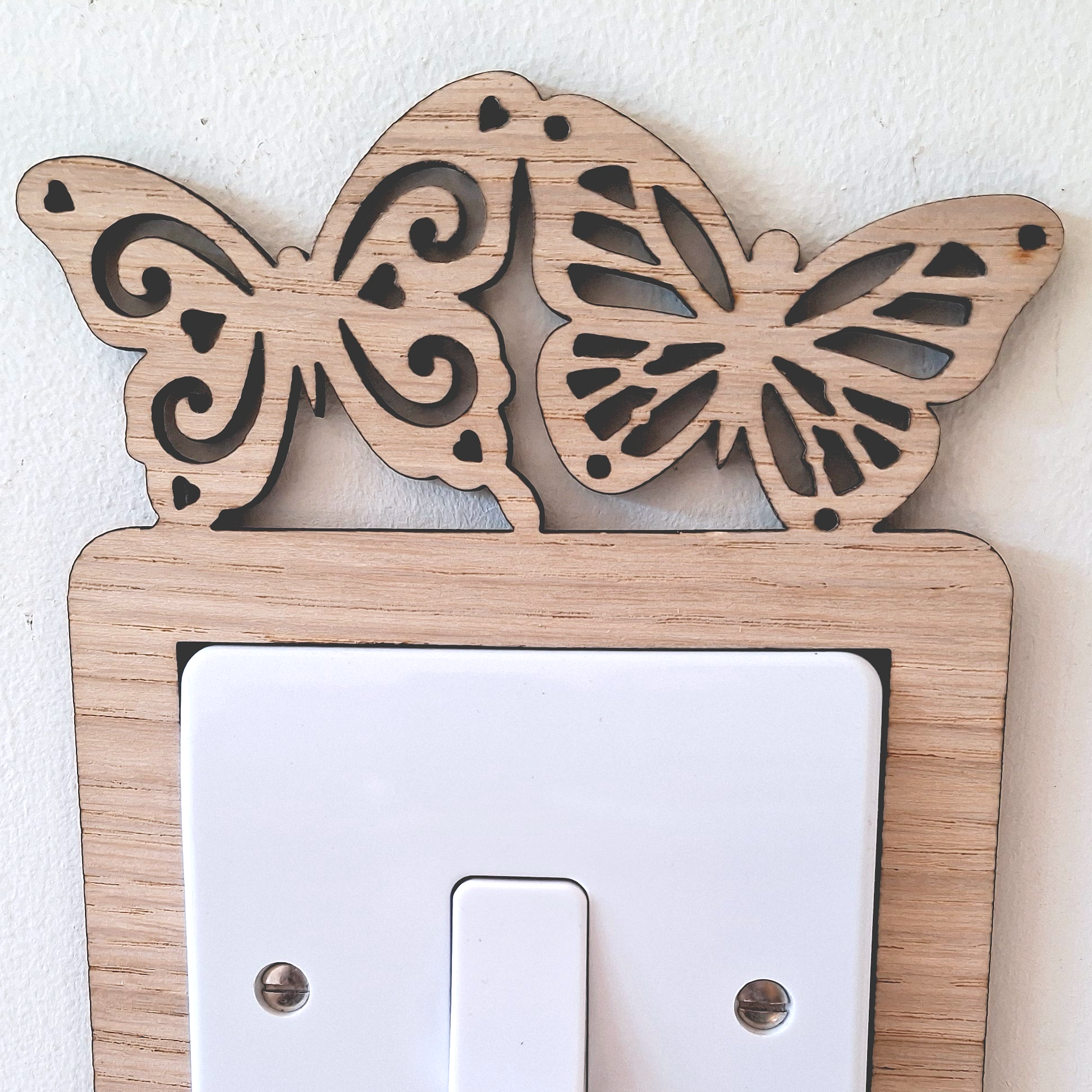 A wooden light switch with a butterfly design on top.