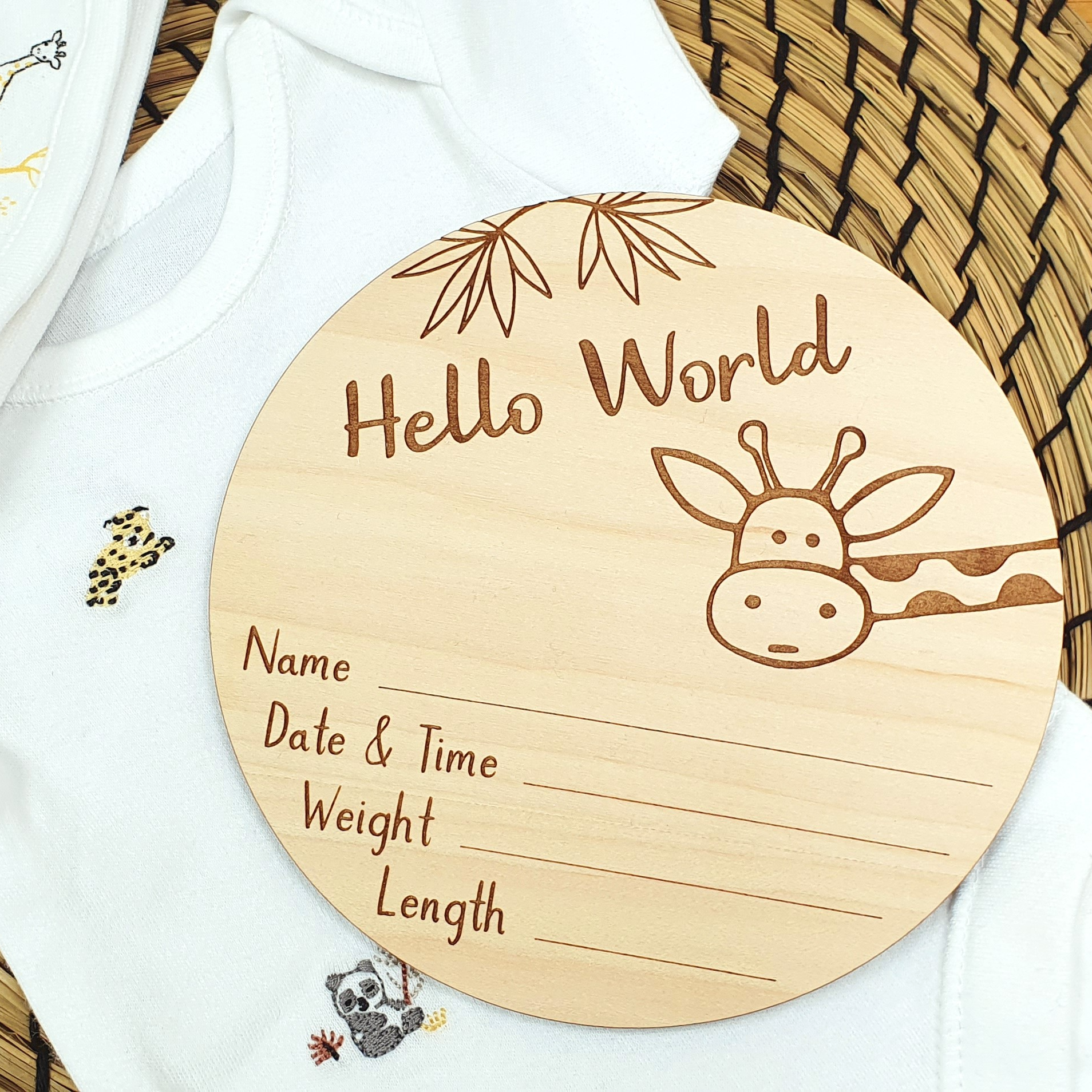 A wooden baby name card with a giraffe illustration and text, placed on a woven basket.