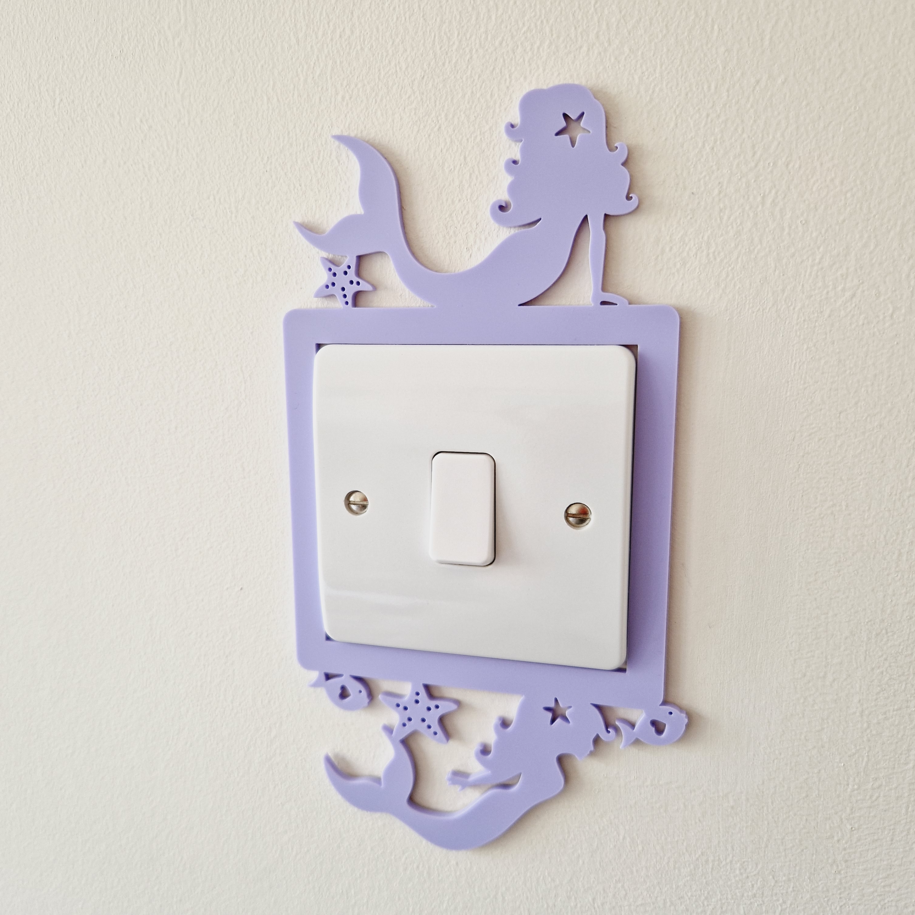A purple mermaid-shaped light switch is mounted on a white wall.