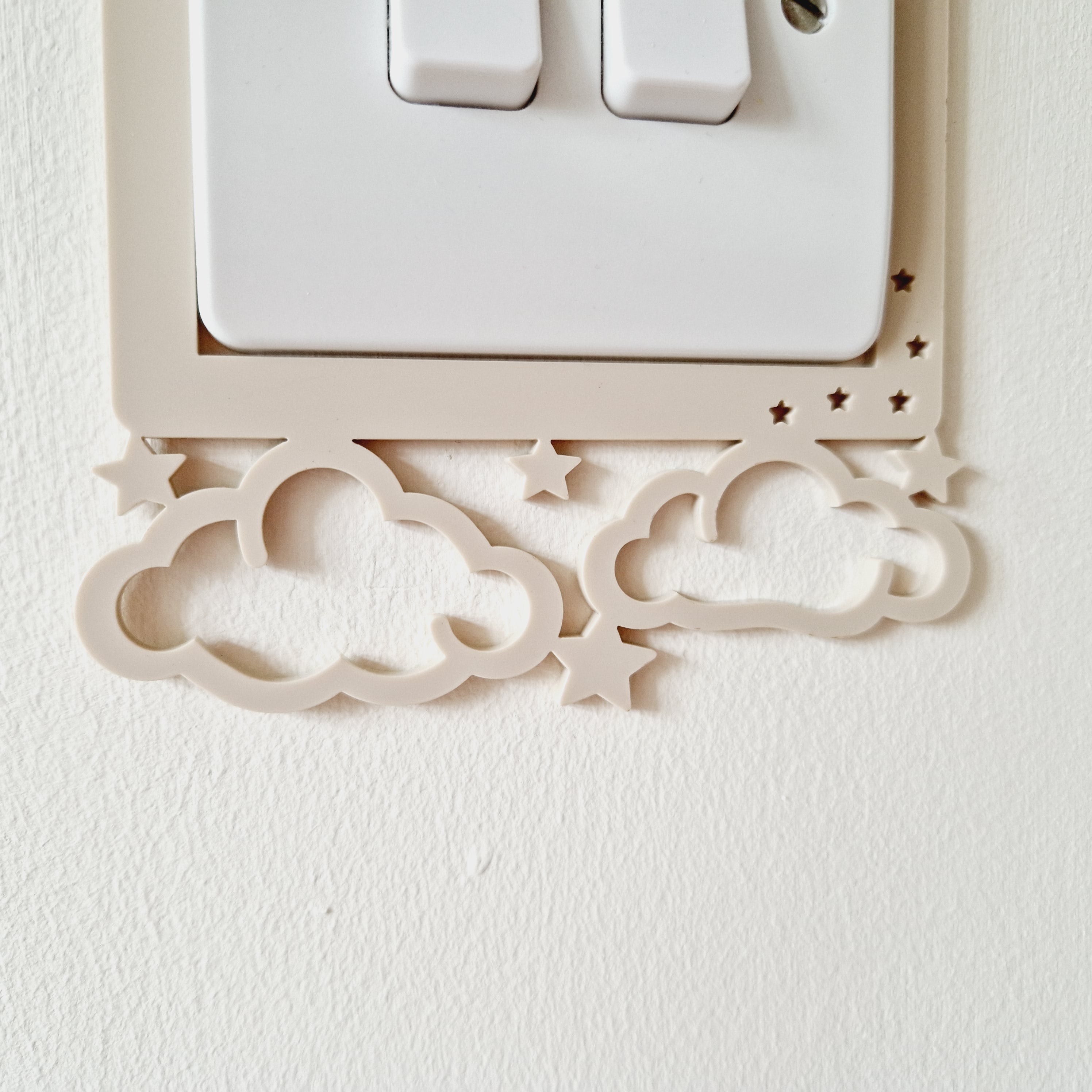 a light switch with a decorative frame featuring clouds and stars.