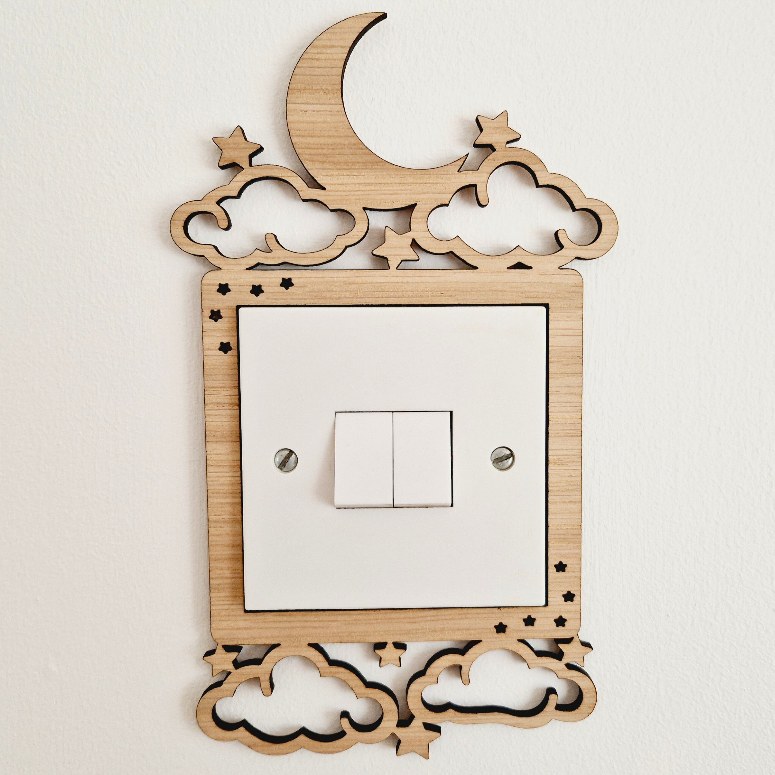 A wooden light switch with a moon and star design on top, featuring a white switch with two light bulbs.