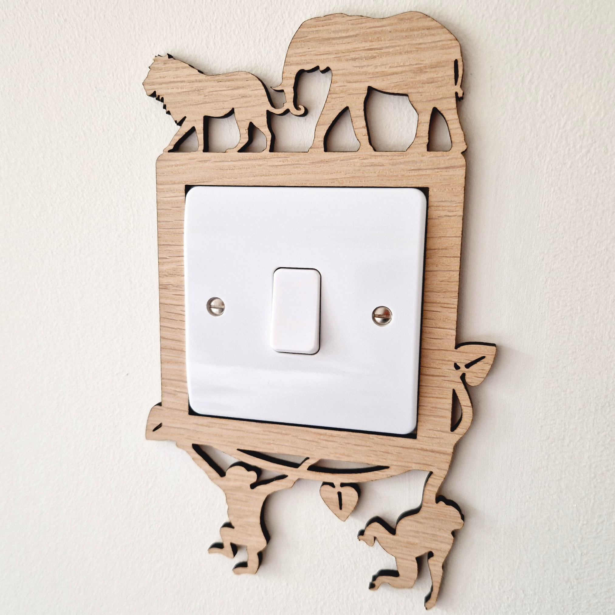 A wooden light switch with a silhouette of an elephant and a lion on it, mounted on a wall.