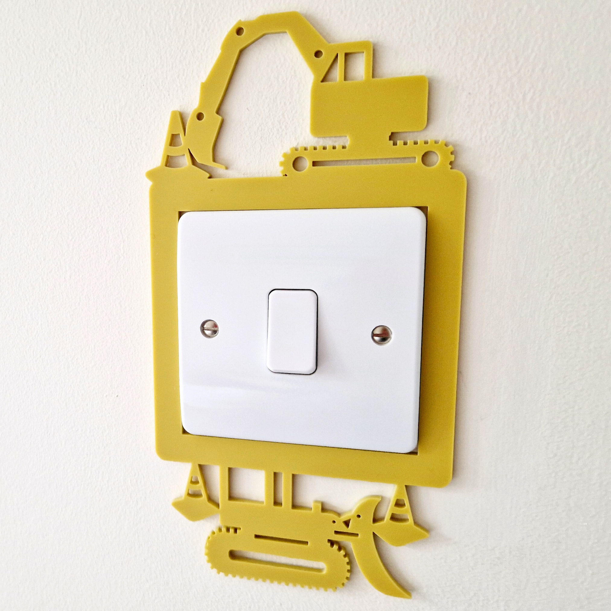 A yellow and white light switch with a playful construction vehicle-shaped frame.