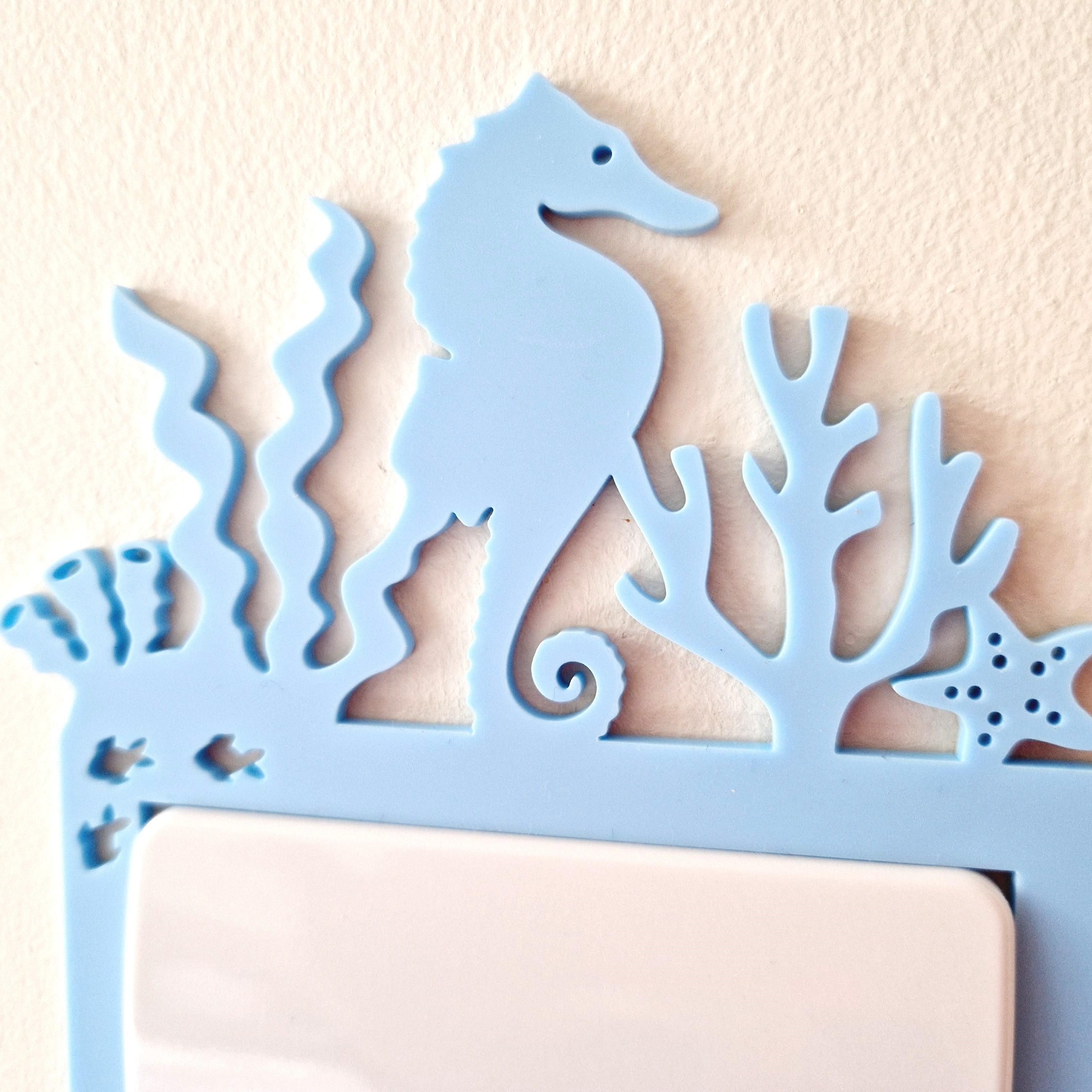 A blue seahorse-shaped light switch on a wall.
