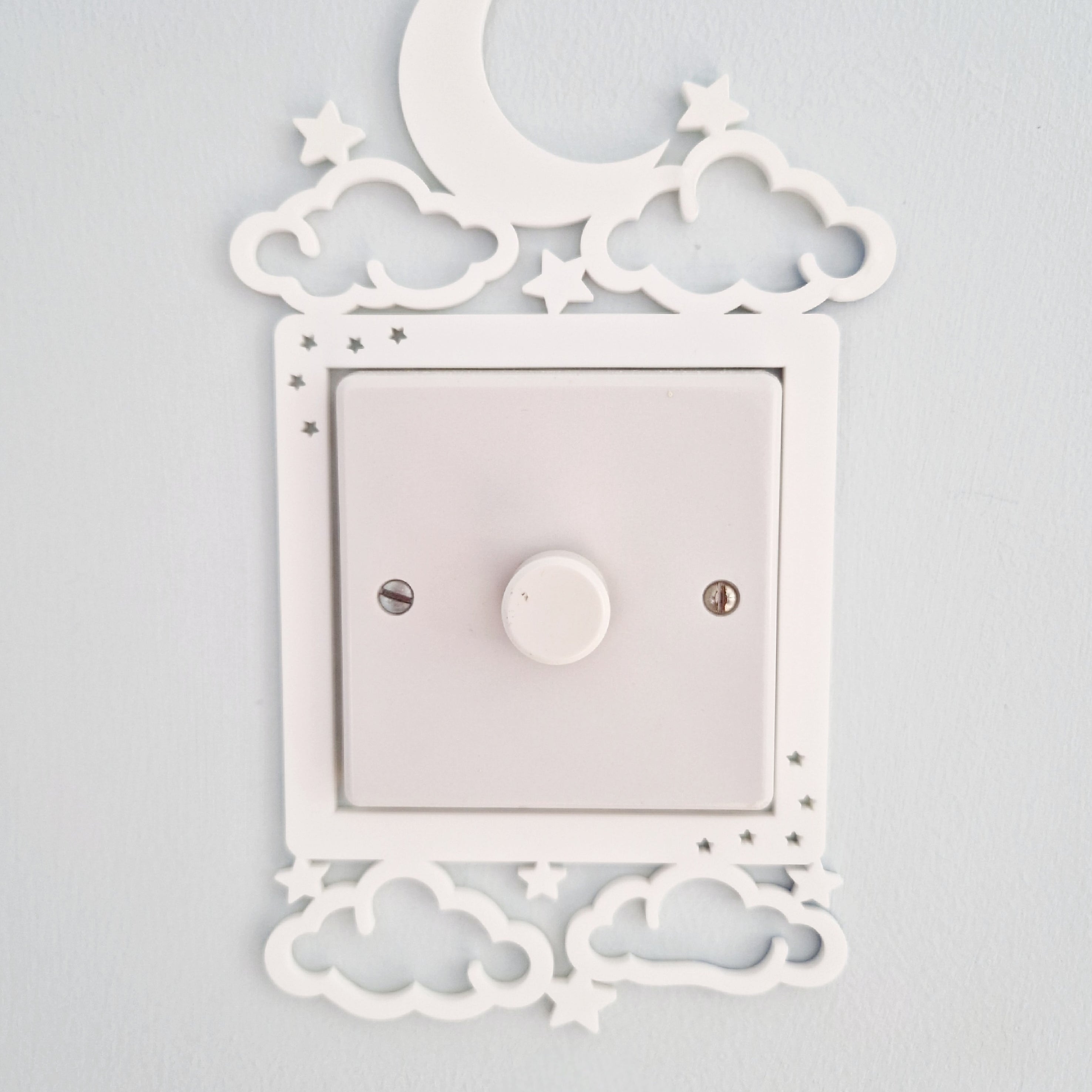 a white light switch with a moon and star decoration above it, mounted on a wall.