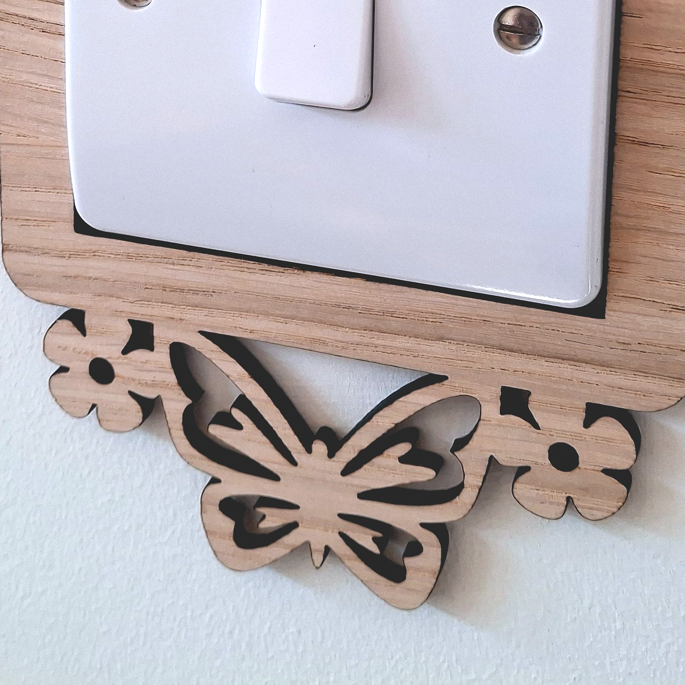A wooden butterfly-shaped light switch cover is mounted on a wall.