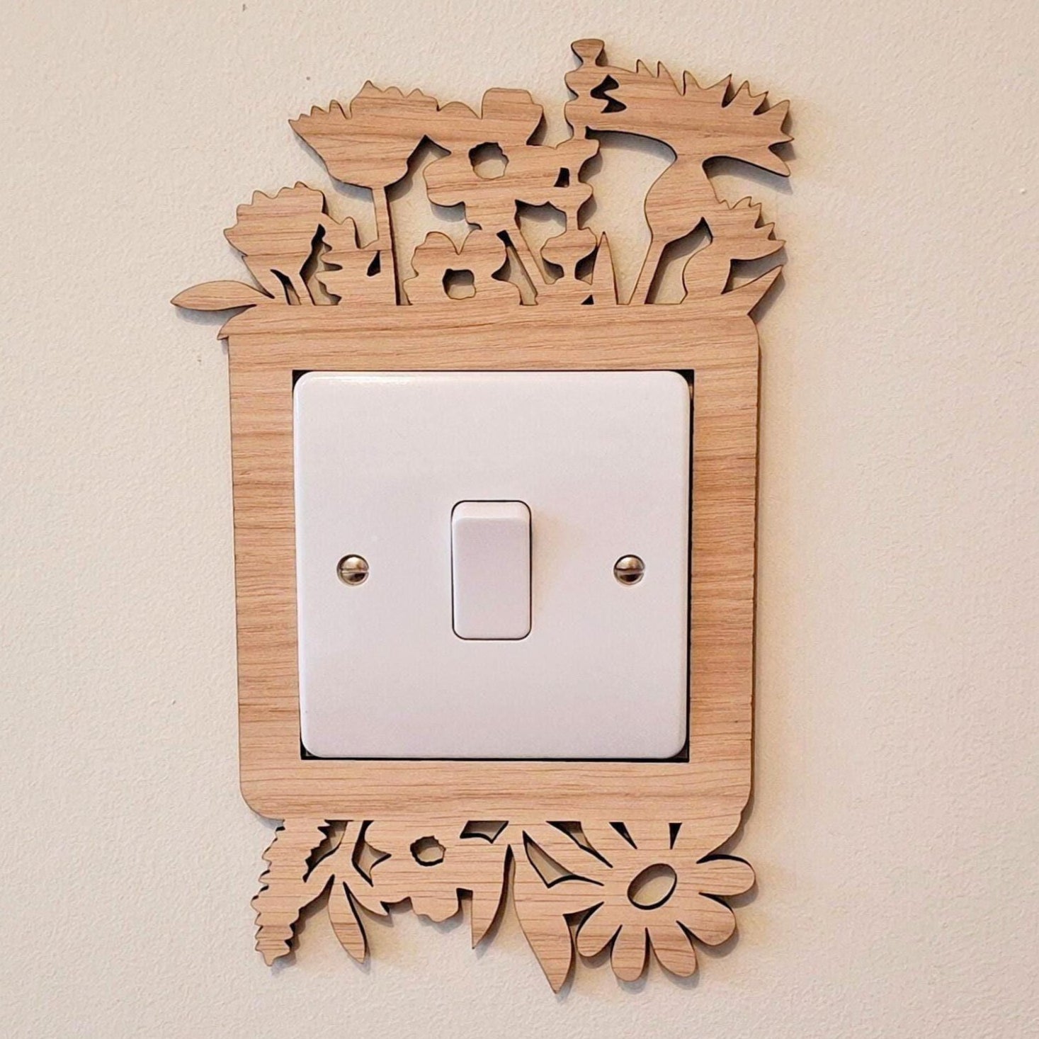 Wooden light switch surround with wildflower design top and bottom.
