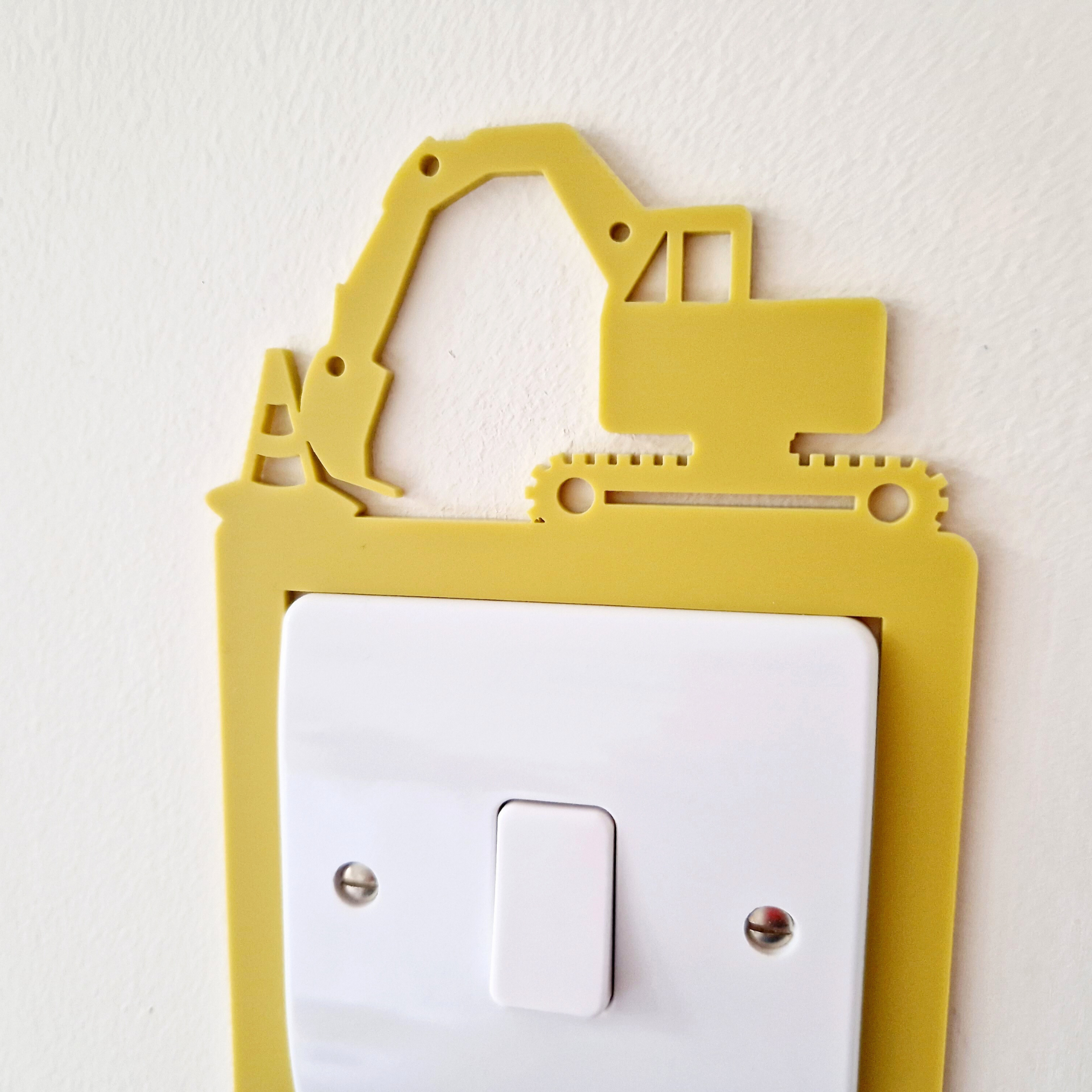 A yellow plastic construction vehicle-shaped light switch on a white wall.