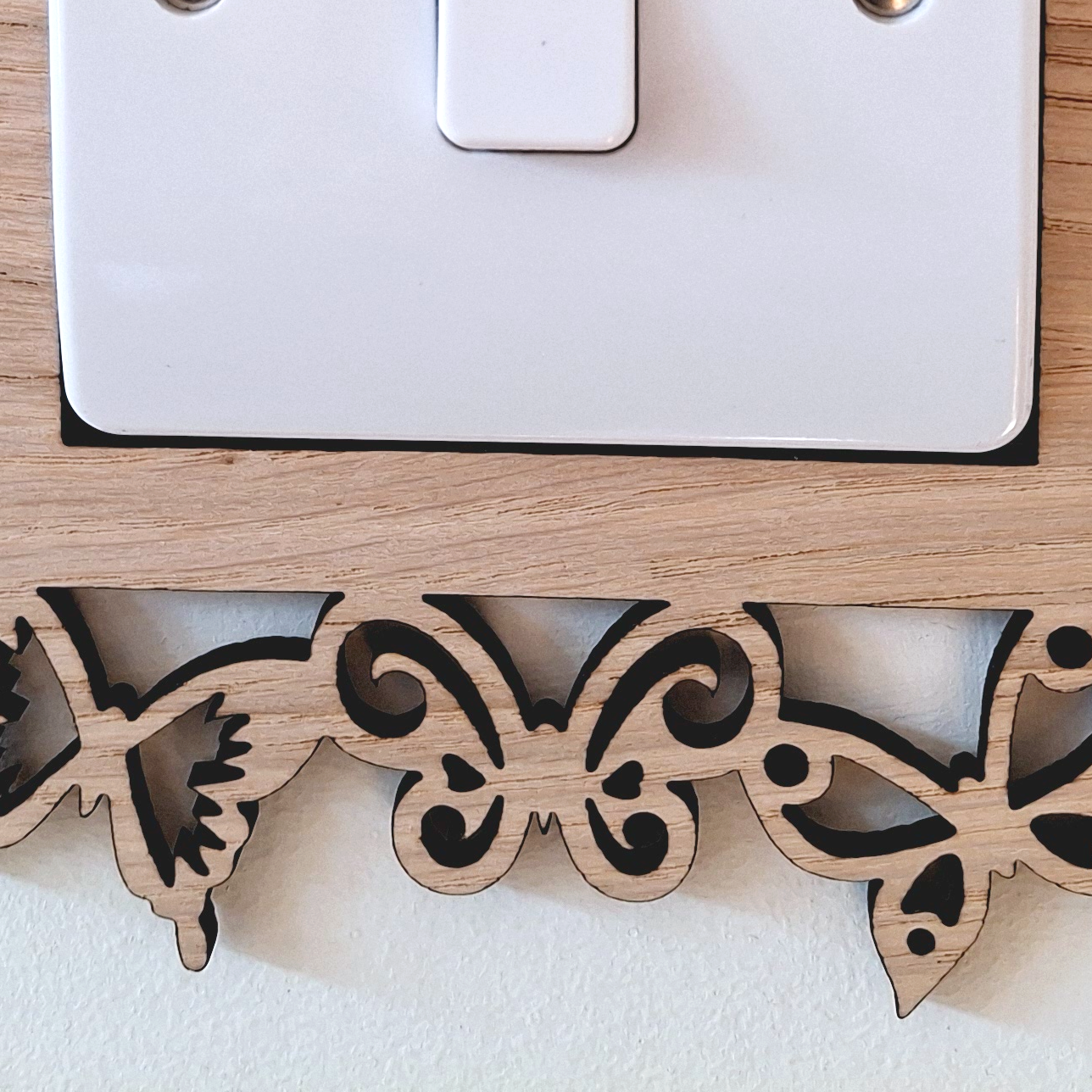A wooden light switch with a butterfly-shaped frame is mounted on a white wall.