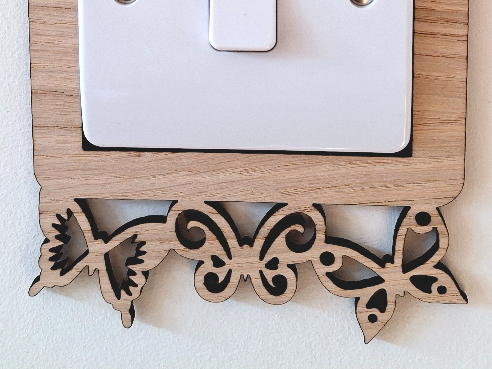A wooden light switch with a butterfly-shaped frame is mounted on a white wall.