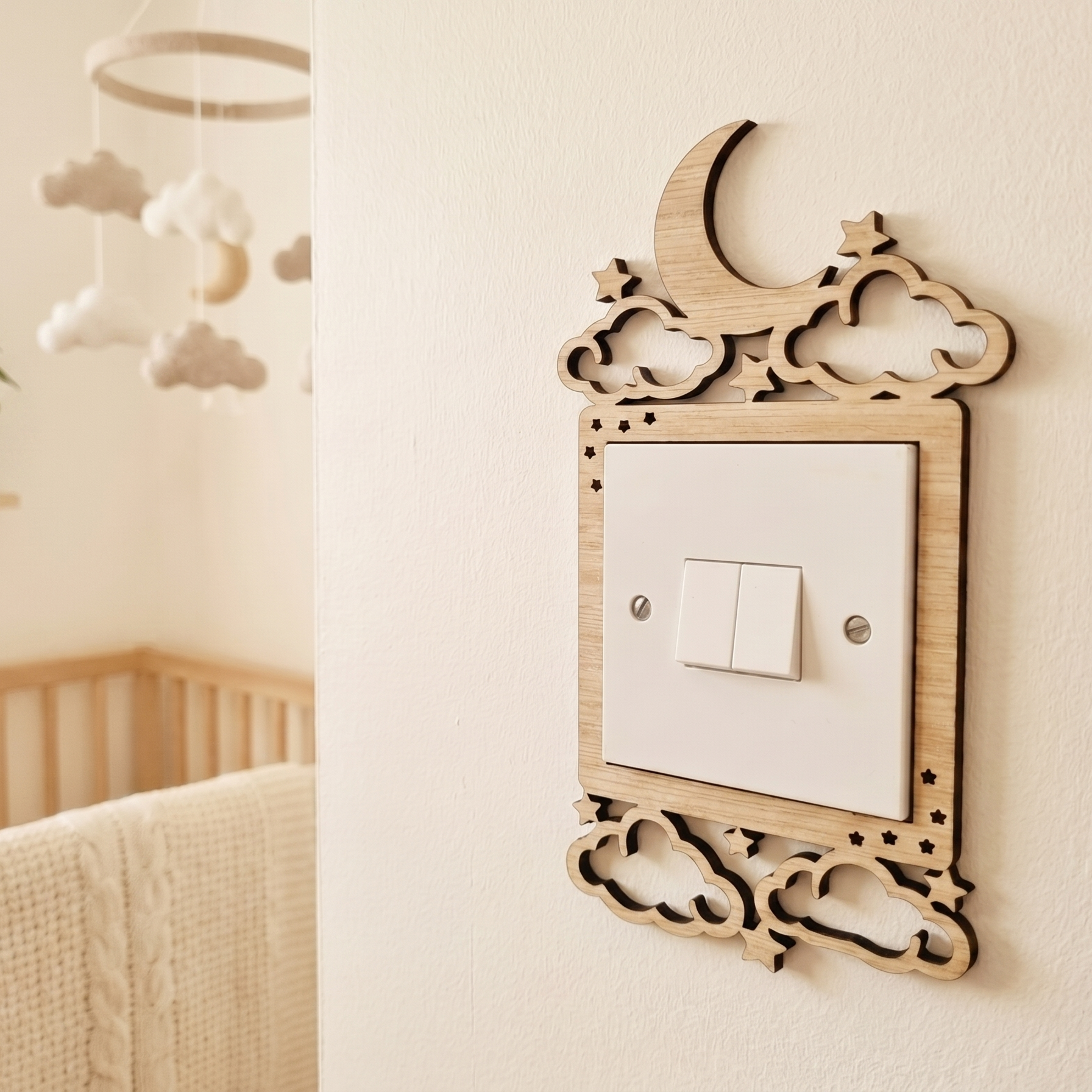 Decorative light switch cover with cloud moon and stars design in wood, on a wall in a nursery.