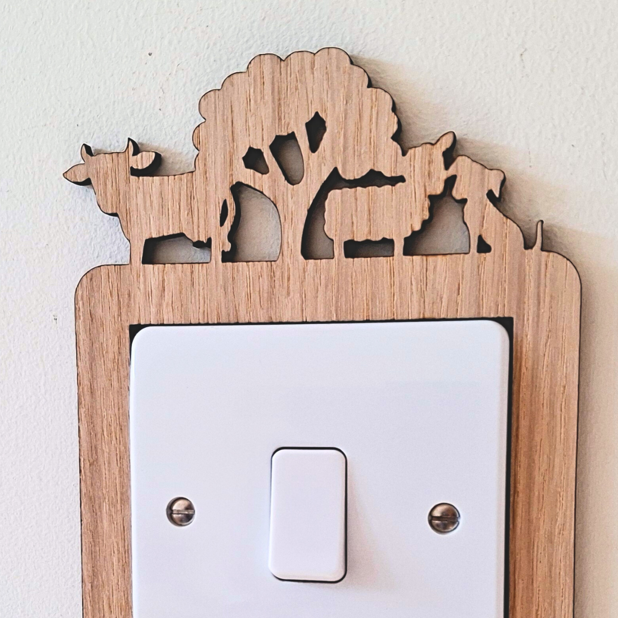 Decorative light switch cover with farmyard animal and tractor cut outs on a white background