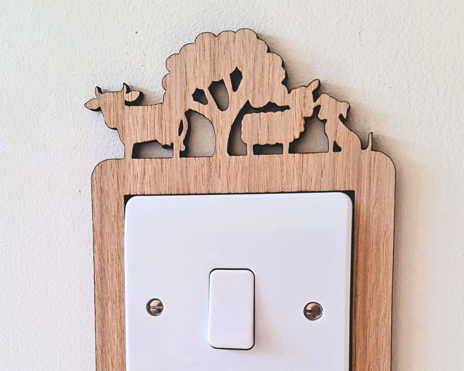 Decorative light switch cover with farmyard animal and tractor cut outs on a white background