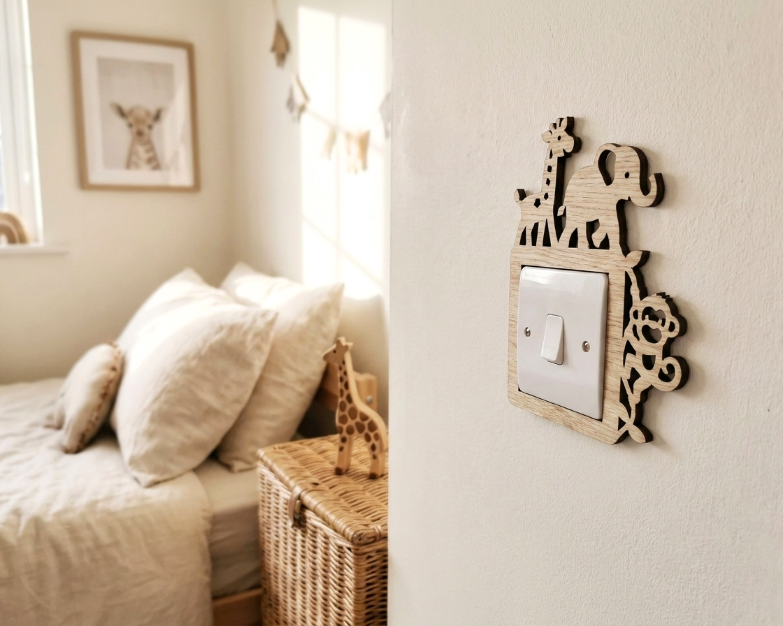 A wooden animal silhouette light switch cover mounted on a white wall in a softly lit bedroom. The cover features cutout shapes of a giraffe, elephant, and monkey around a white switch plate.