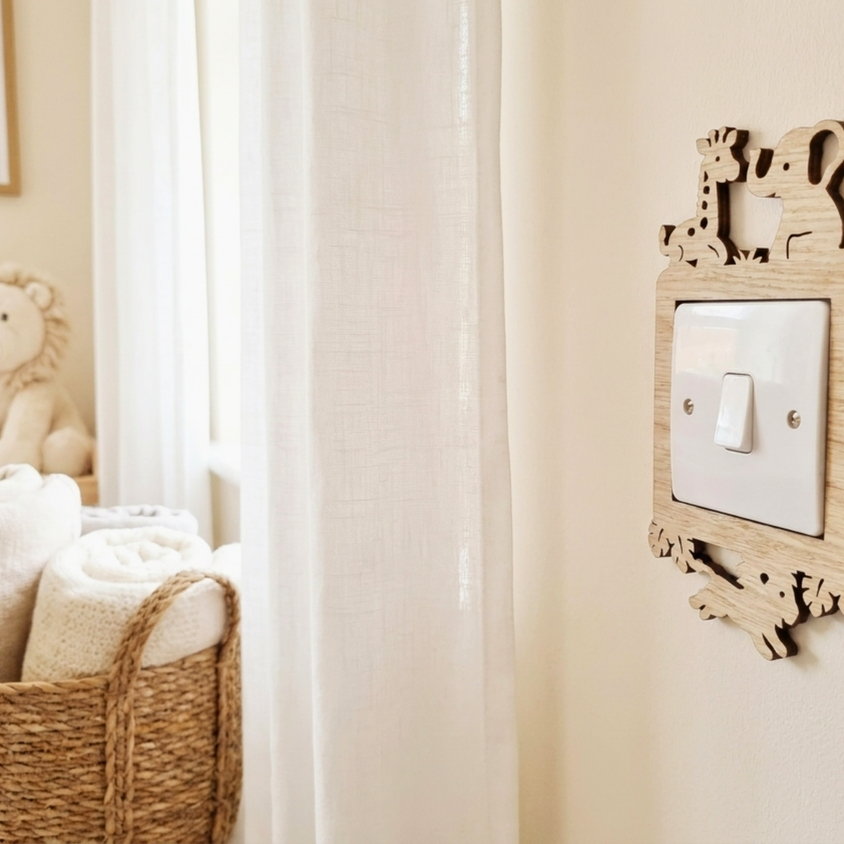 A light switch cover featuring a natural wood frame with animal cutouts of a giraffe, elephant, and monkey, mounted on a beige wall next to a window with sheer curtains.