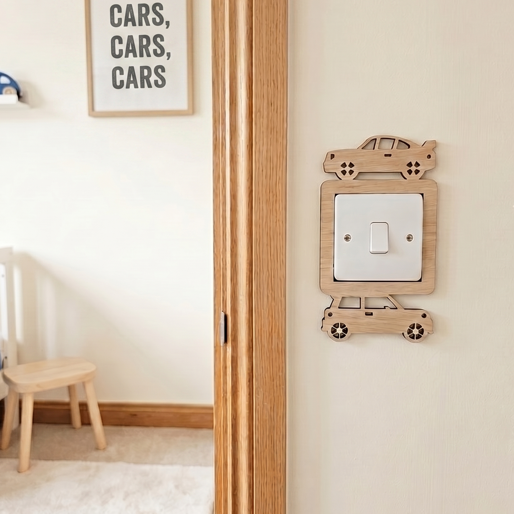 Wooden car themed light switch surround on the wall outside a children's room with a bed, chair, and wall decor featuring the word 'cars'.