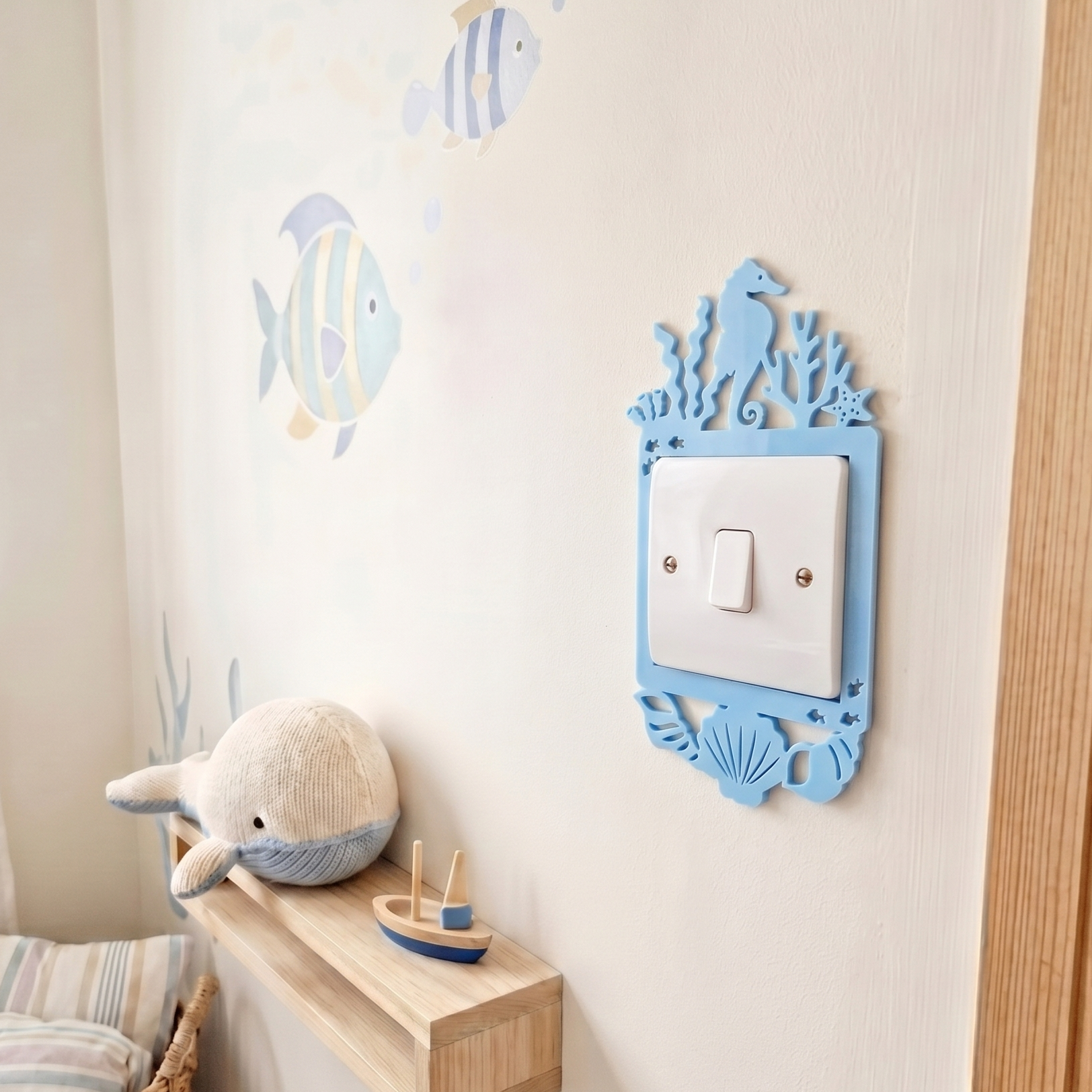 Children's room with an ocean themed decorative light switch cover, plush toy, and wall stickers.