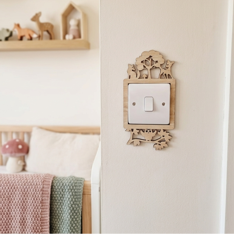 Decorative wooden light switch cover with woodland fox, deer and owl design in a nursery setting.