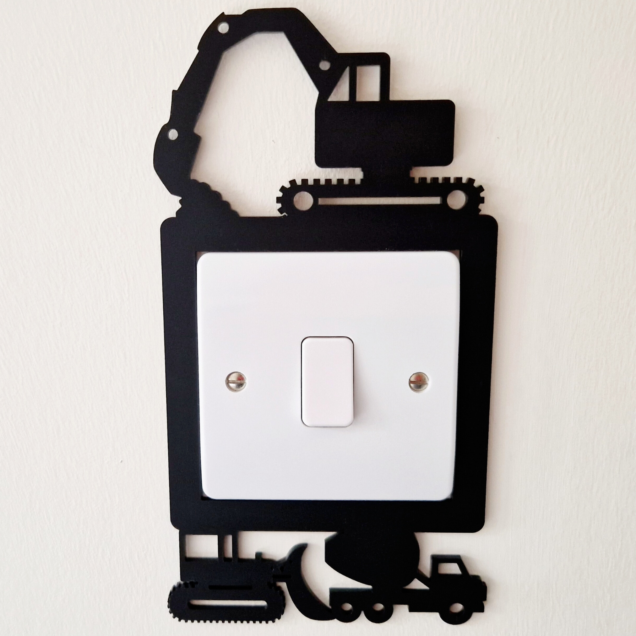 A wall-mounted light switch with a black and white design featuring construction vehicles and equipment.