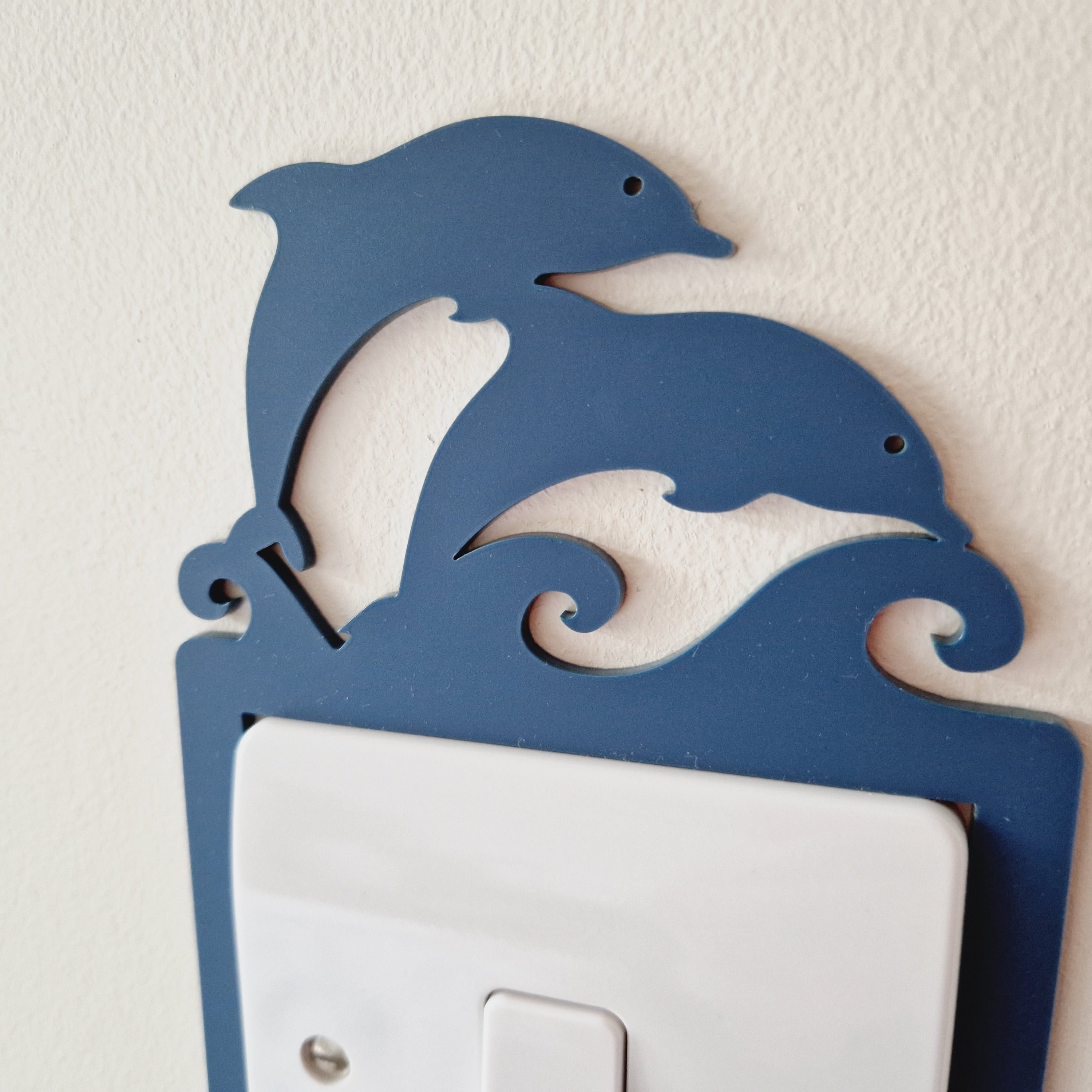 A blue dolphin-shaped light switch on a wall.