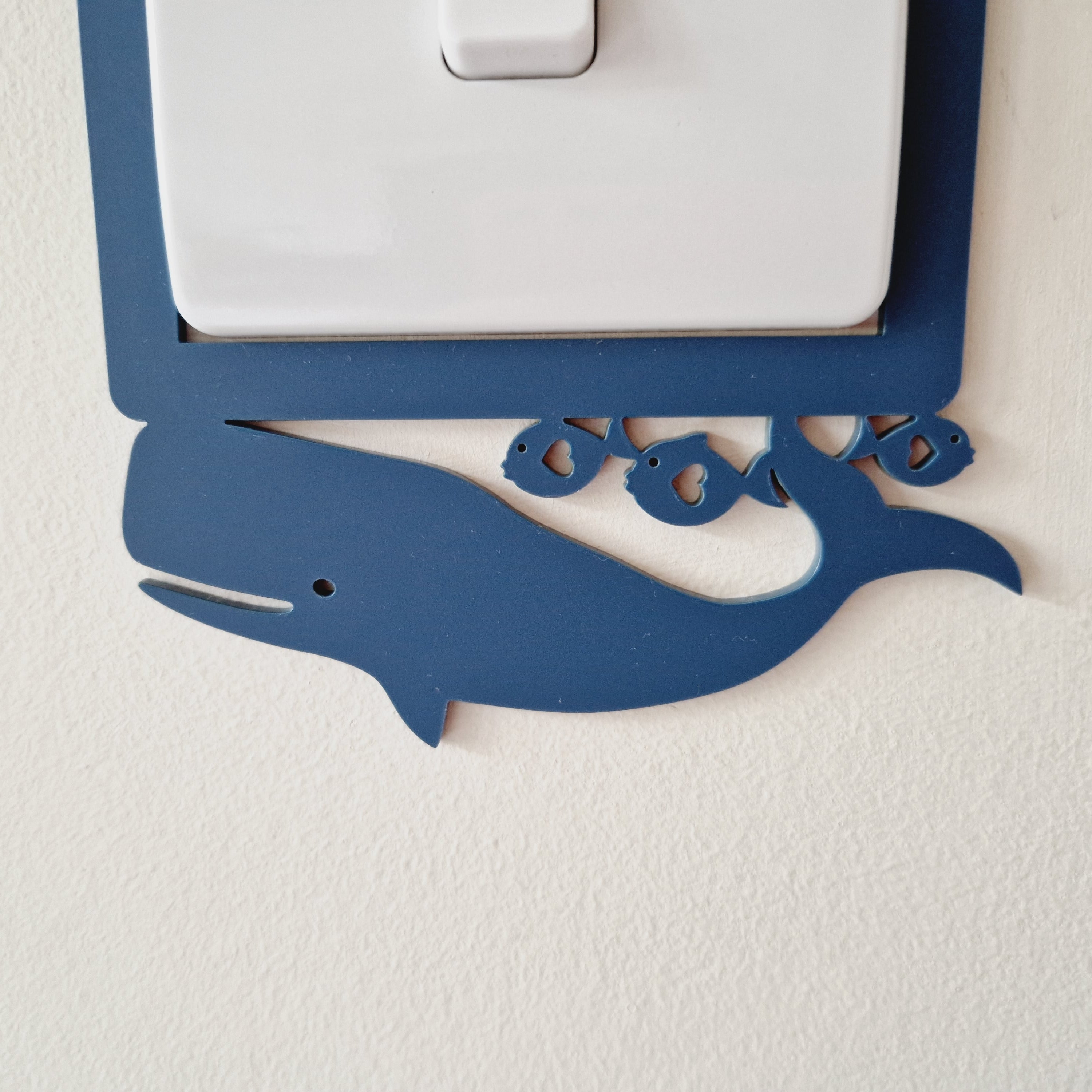 A light switch with a blue whale decoration on the plate.