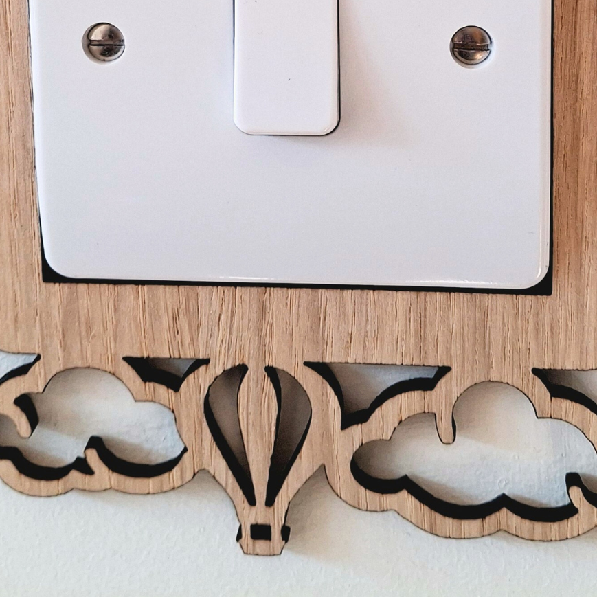 A wooden light switch with two hot air balloons mounted on top of it.
