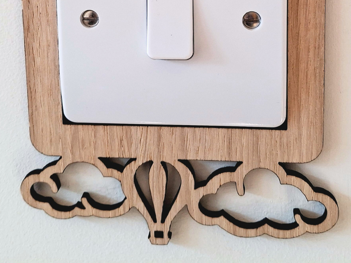 A wooden light switch with two hot air balloons mounted on top of it.
