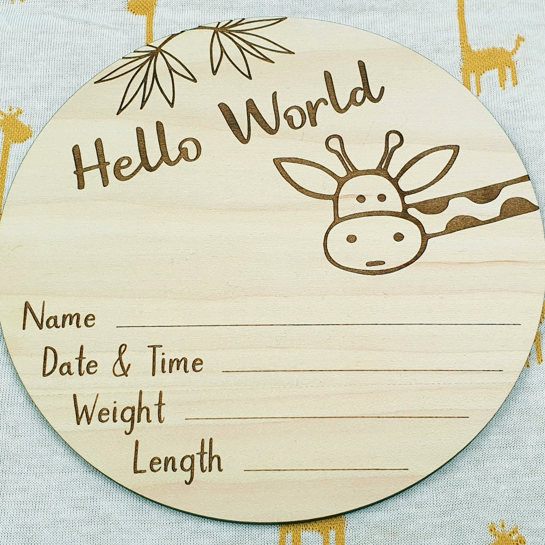 a wooden plaque with a giraffe design, placed on a surface with a repeating pattern of yellow giraffes.
