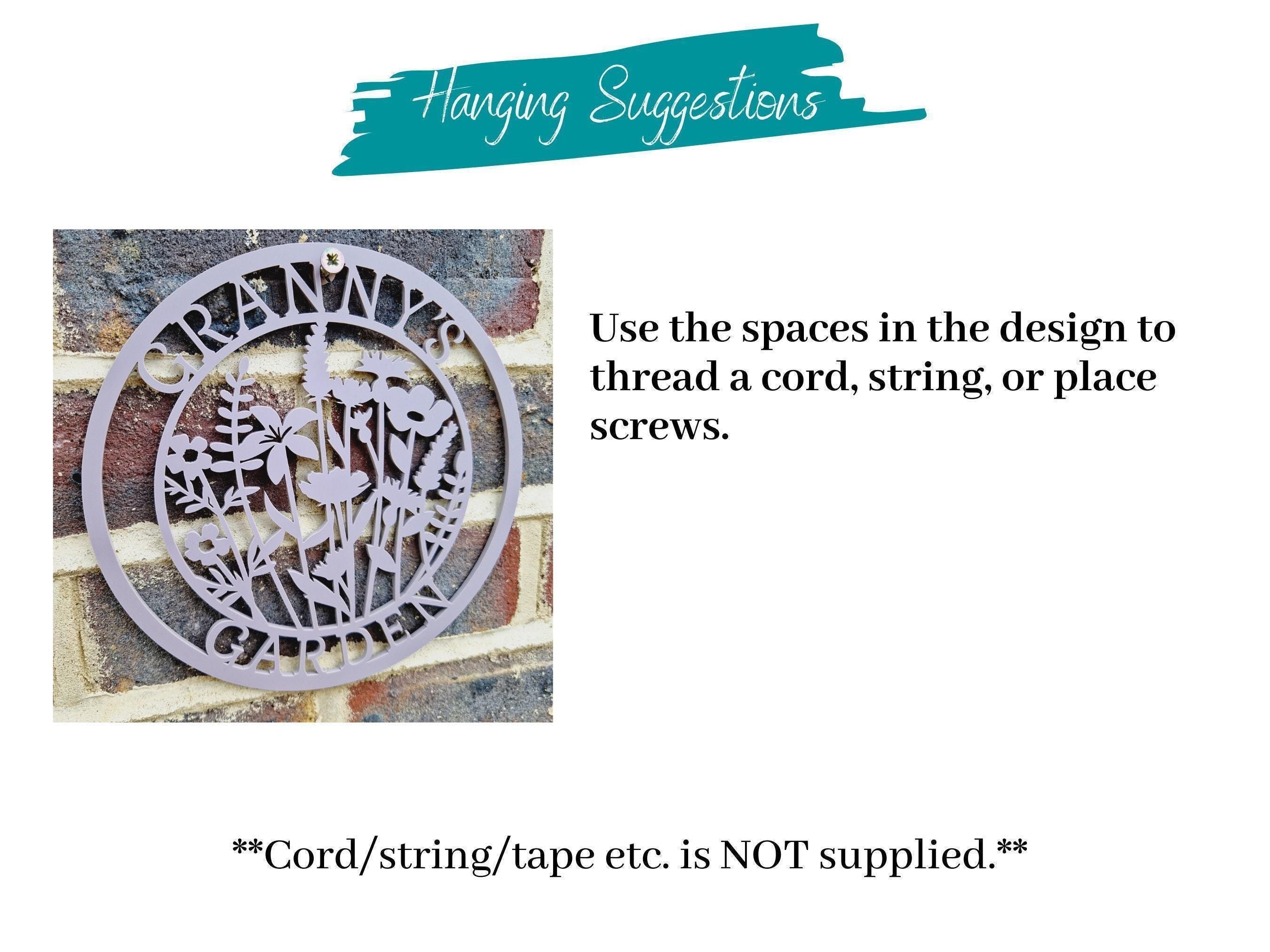 Decorative acrylic floral sign with text on how to install it, placed on a brick background.