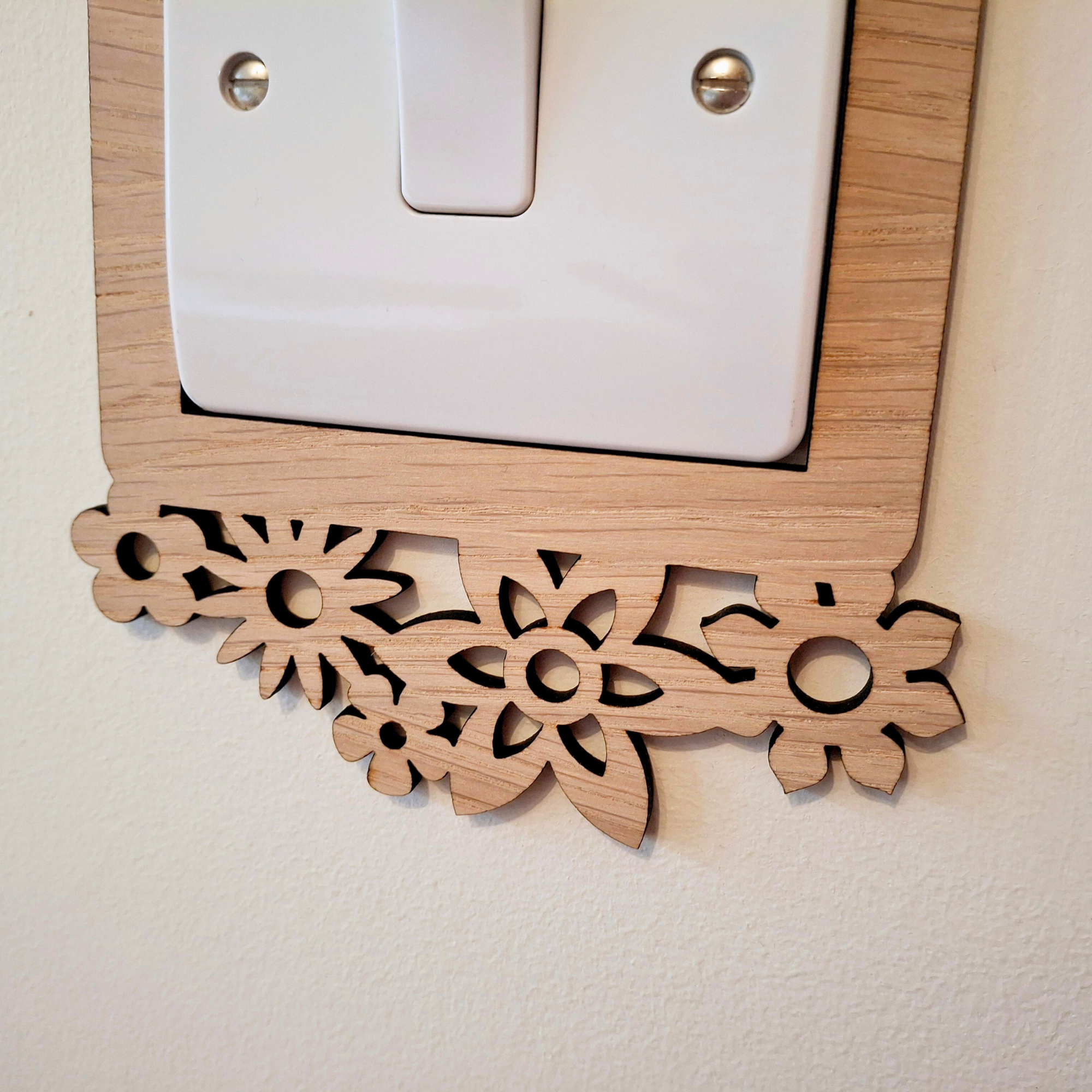 a wooden switch plate with a decorative floral design on it, mounted on a wall.