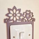 A purple floral design is mounted on a light switch, creating a decorative element on the wall.
