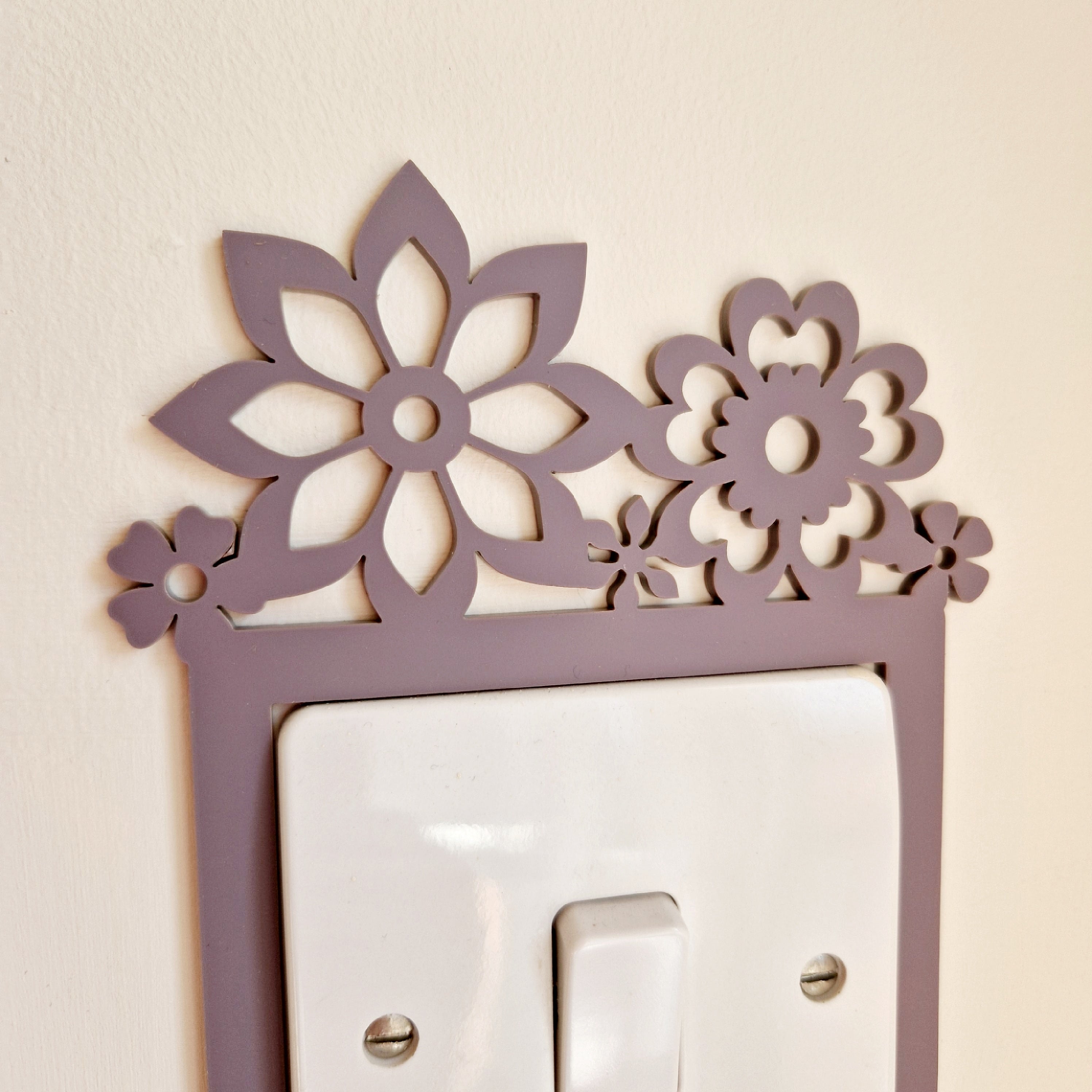 A purple floral design is mounted on a light switch, creating a decorative element on the wall.