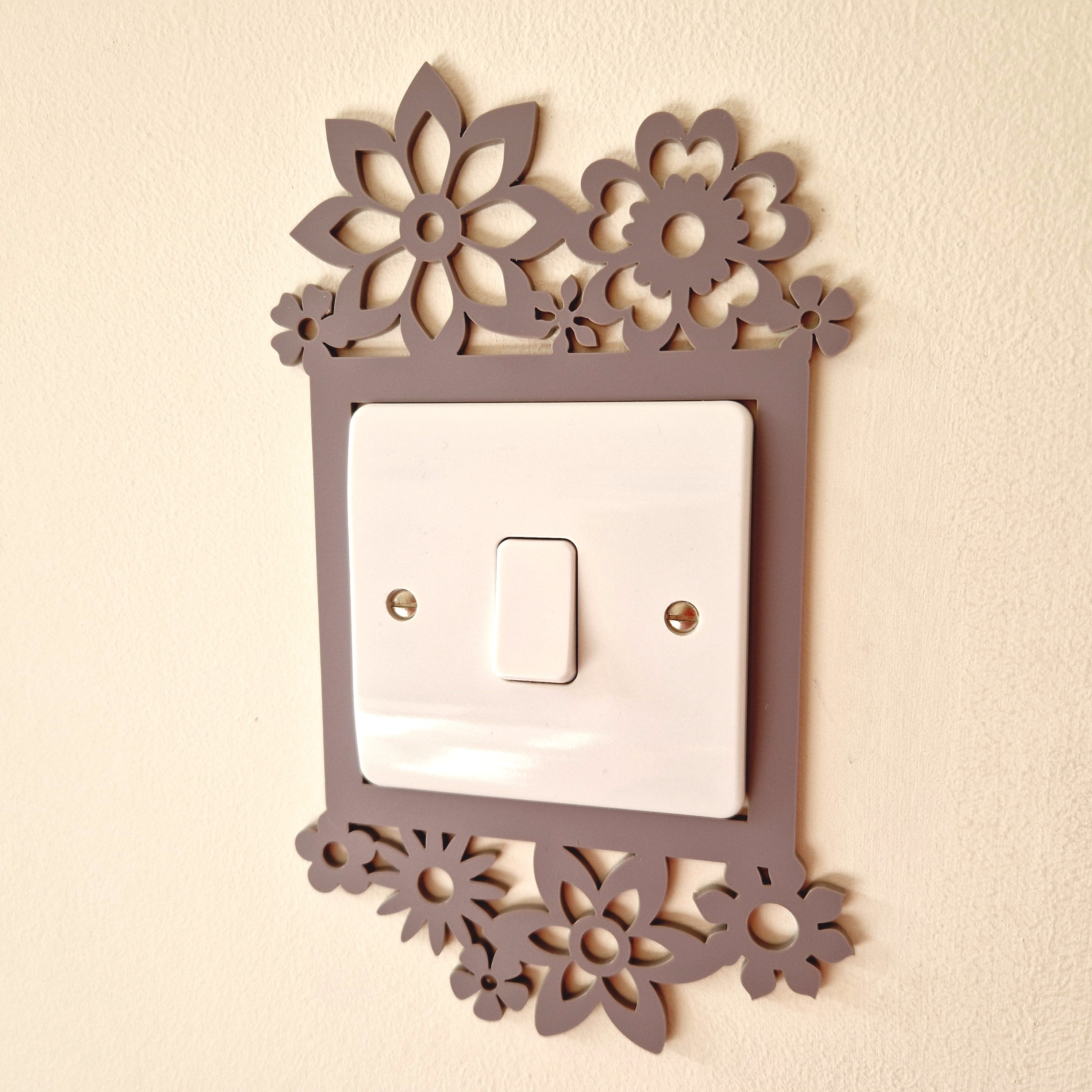 a wall-mounted light switch with a decorative floral design surrounding it.