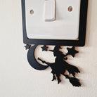 Decorative black silhouette of a witch on a broom, on a light switch cover 