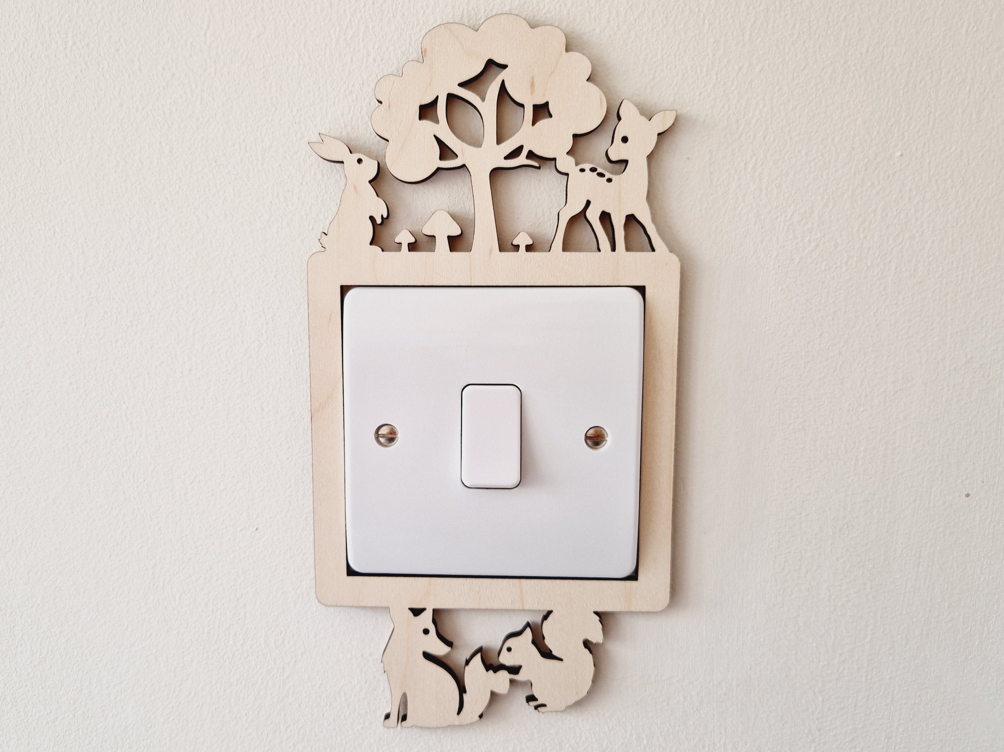 Decorative light switch cover with woodland bunny, deer, fox and squirrel animal design on a plain wall.