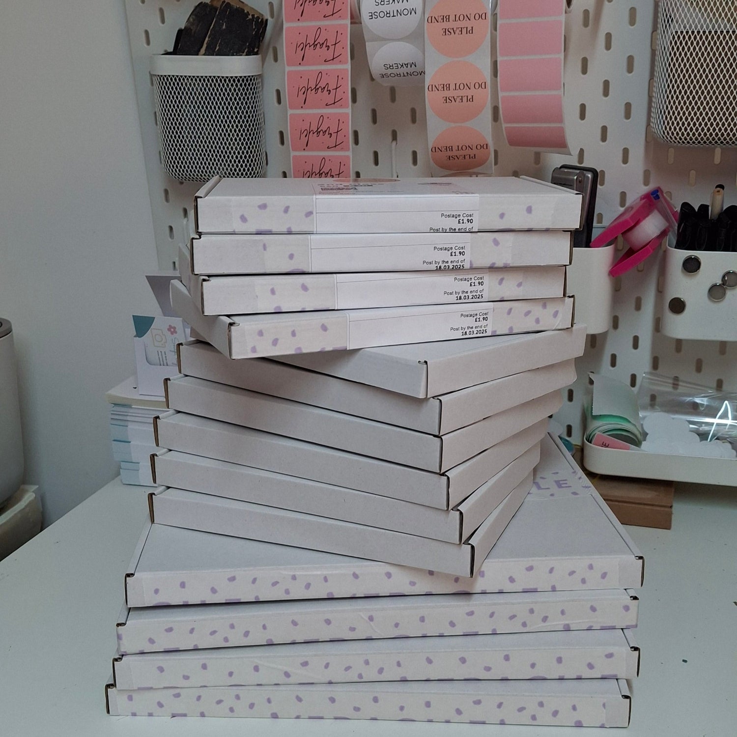 Stacks of white boxes and pink labels on a shelf in a room.