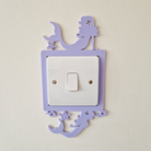 A purple light switch with a mermaid and starfish design on it, mounted on a wall.
