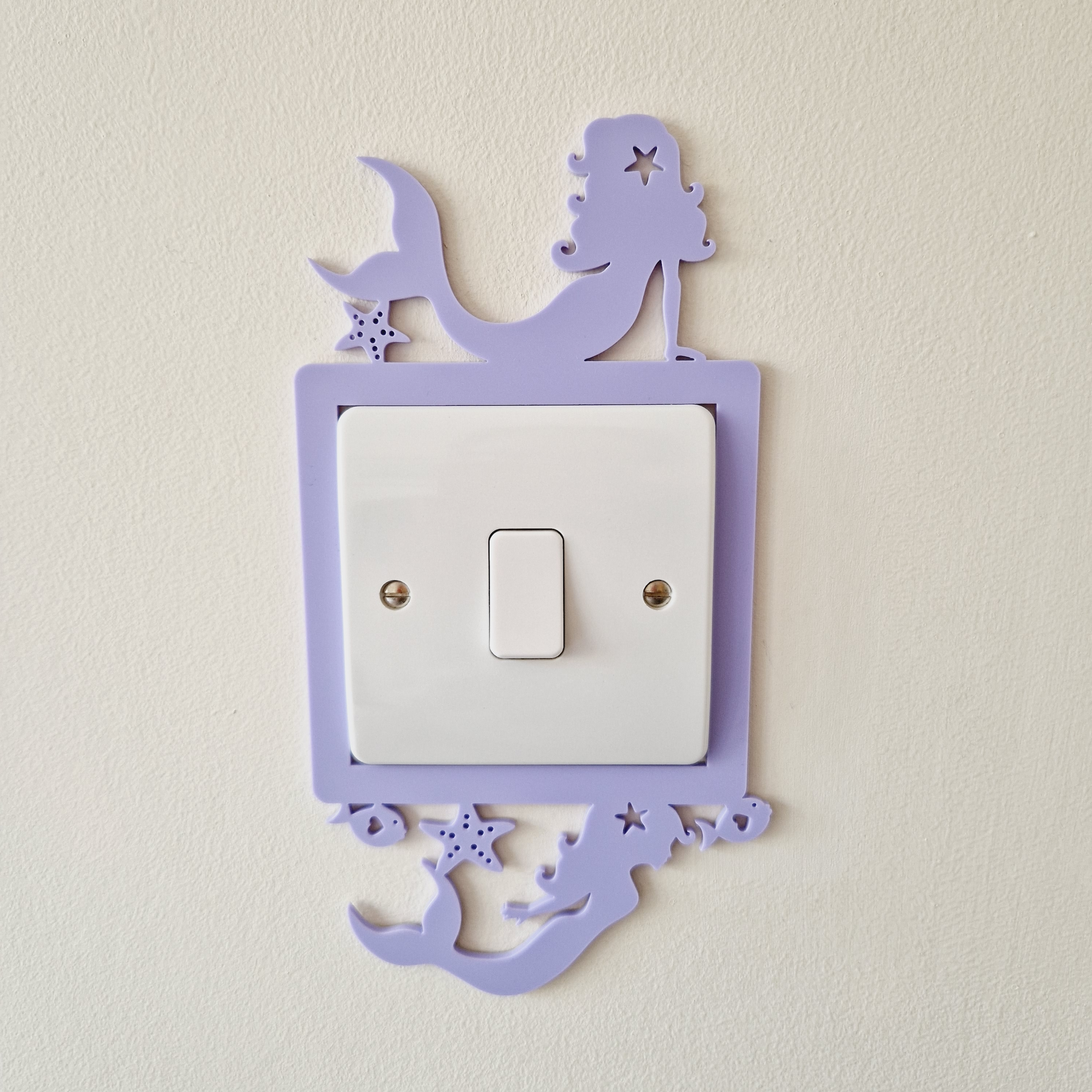 A purple light switch with a mermaid and starfish design on it, mounted on a wall.