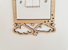 a wooden light switch with a decorative design featuring clouds and stars carved into the switch itself.