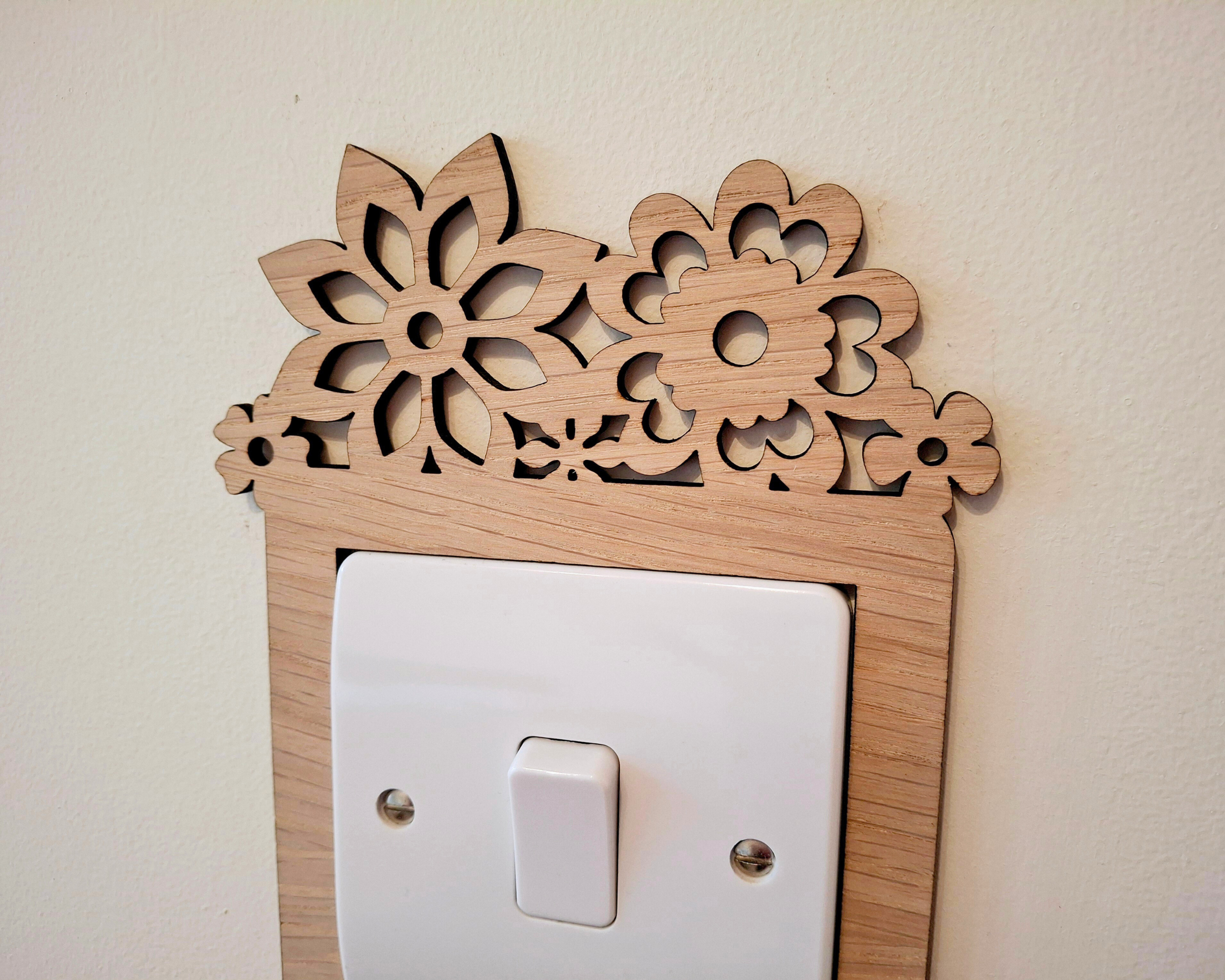 A wooden decorative piece with a floral pattern is mounted on a wall above a white light switch.