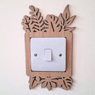 A wooden light switch with a leaf-shaped design on the top and bottom edges, mounted on a white wall.