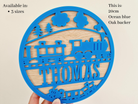 a blue circular cutout with a train design, and the name "THOMAS" written on it.