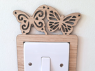 A wooden light switch with a butterfly design on top.