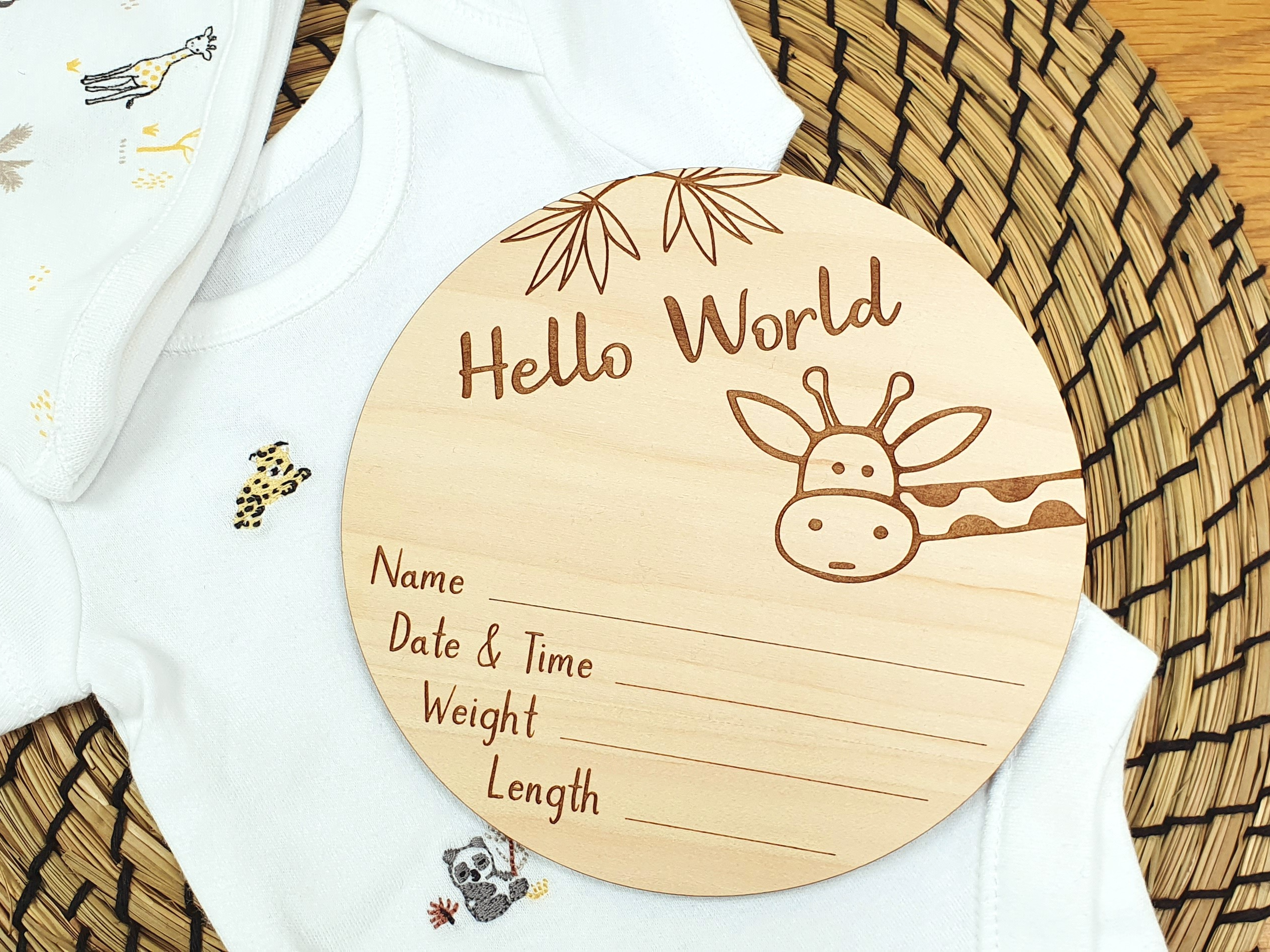A wooden baby name card with a giraffe illustration and text, placed on a woven basket.